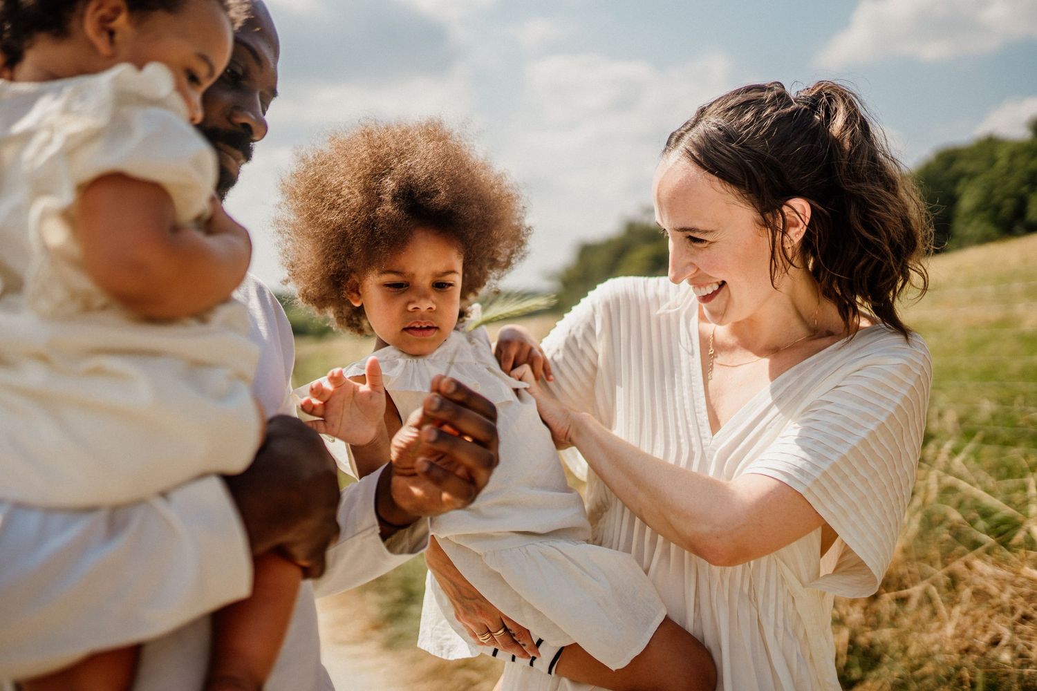 A playful outdoor family moment captured in a sunny meadow.