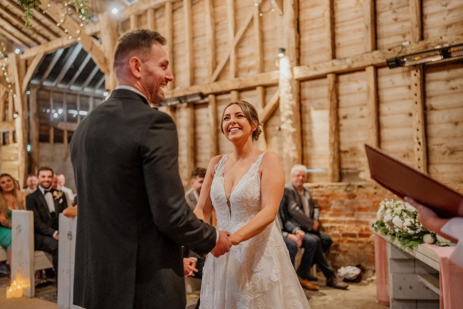 Rustic barn wedding ceremony with wooden beams and romantic lighting.