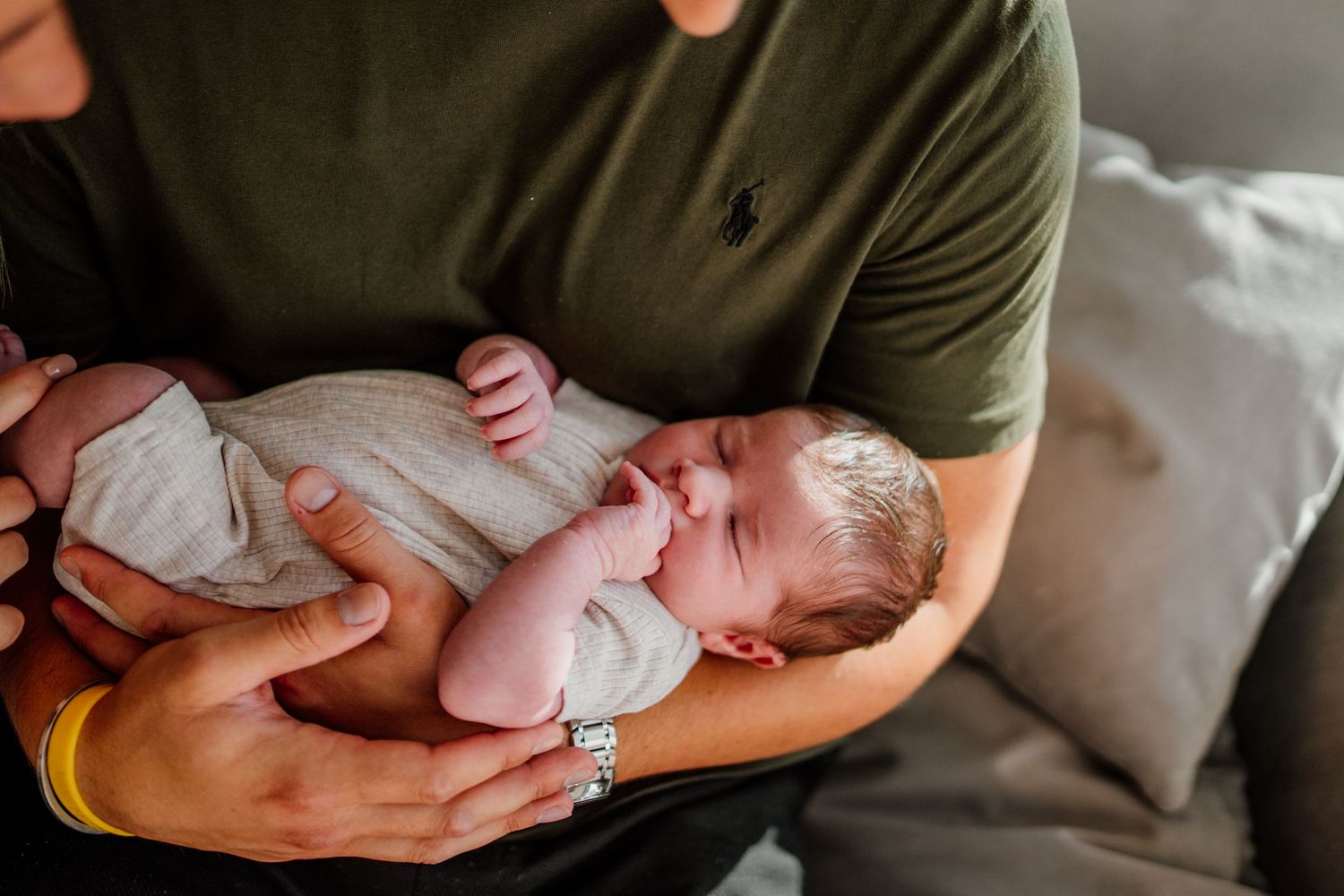 Parents holding and admiring their newborn baby in casual home setting.