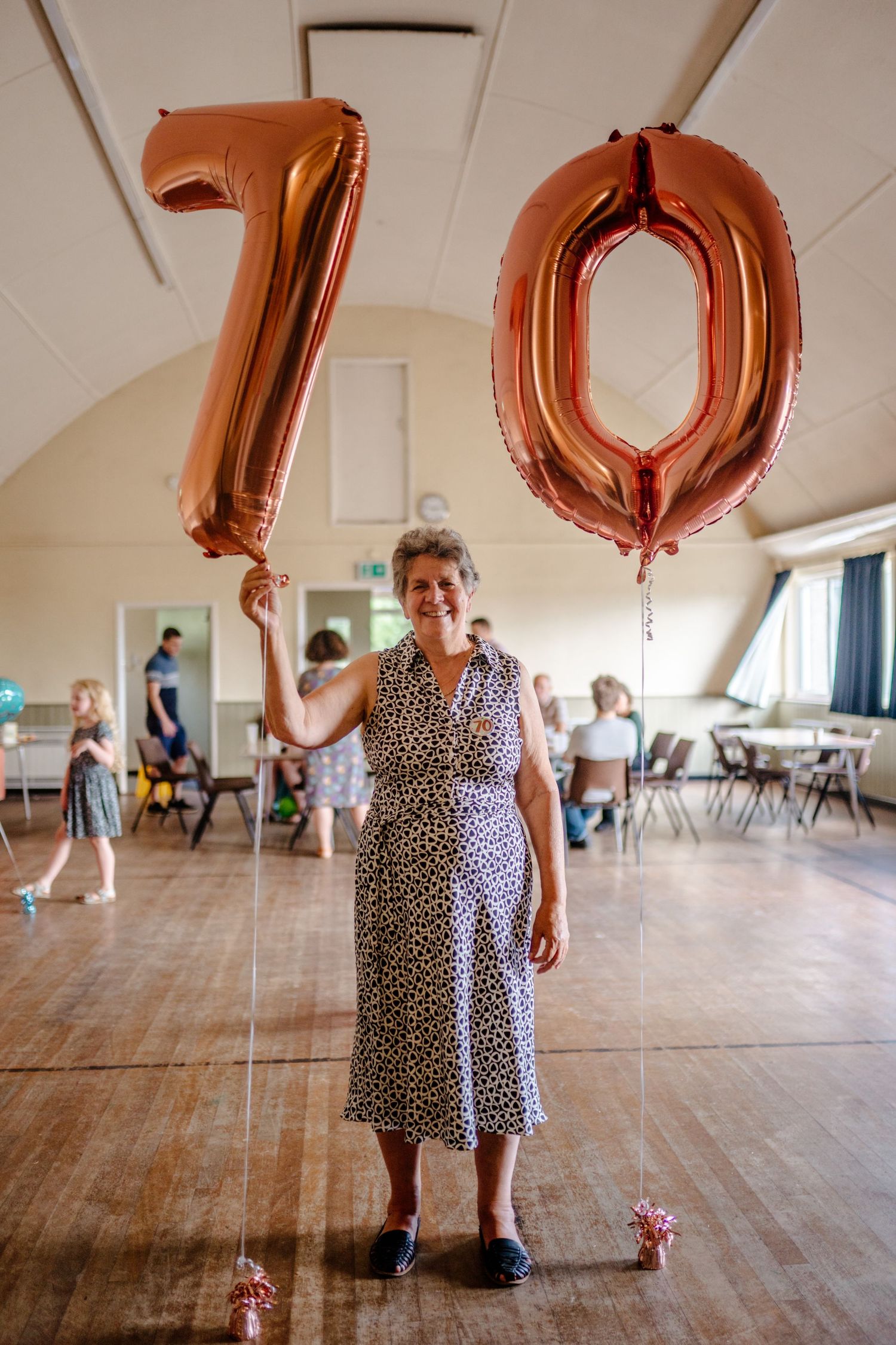 Large copper-colored number balloons decorating a spacious wooden floor venue.