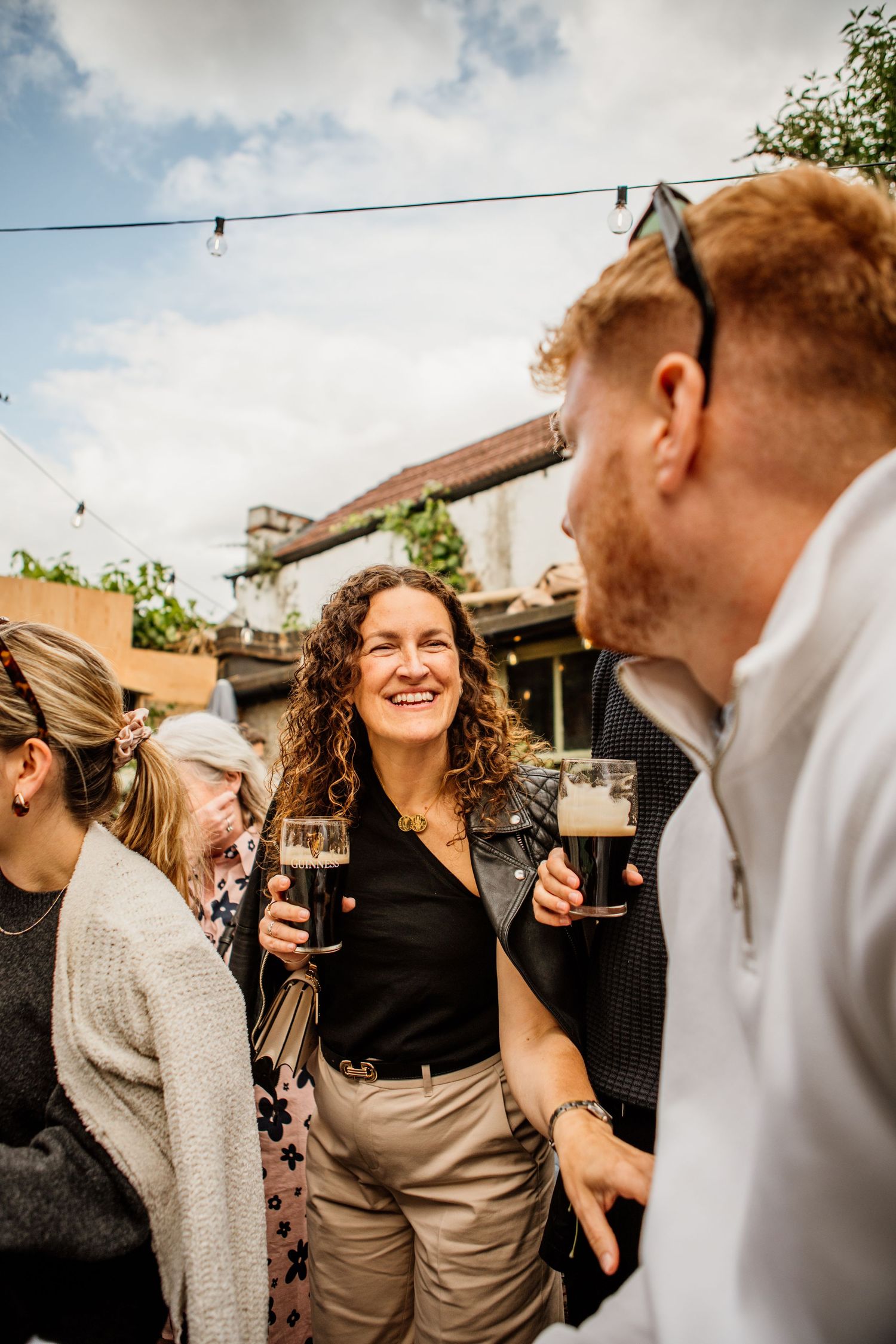 Guests laughing and socializing during an outdoor celebration under cloudy skies.