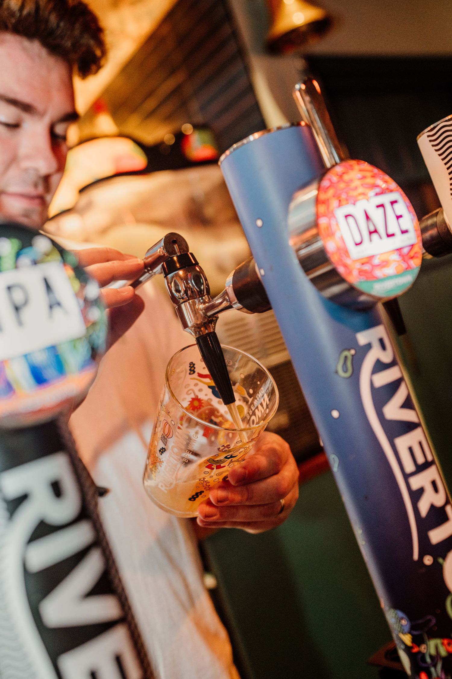 Beer taps and glasses being filled at a craft brewery bar.
