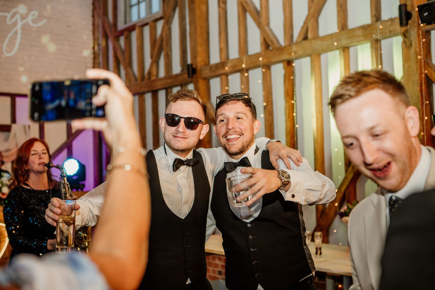 Guests celebrating at a rustic barn wedding reception raise their drinks in a joyful toast.