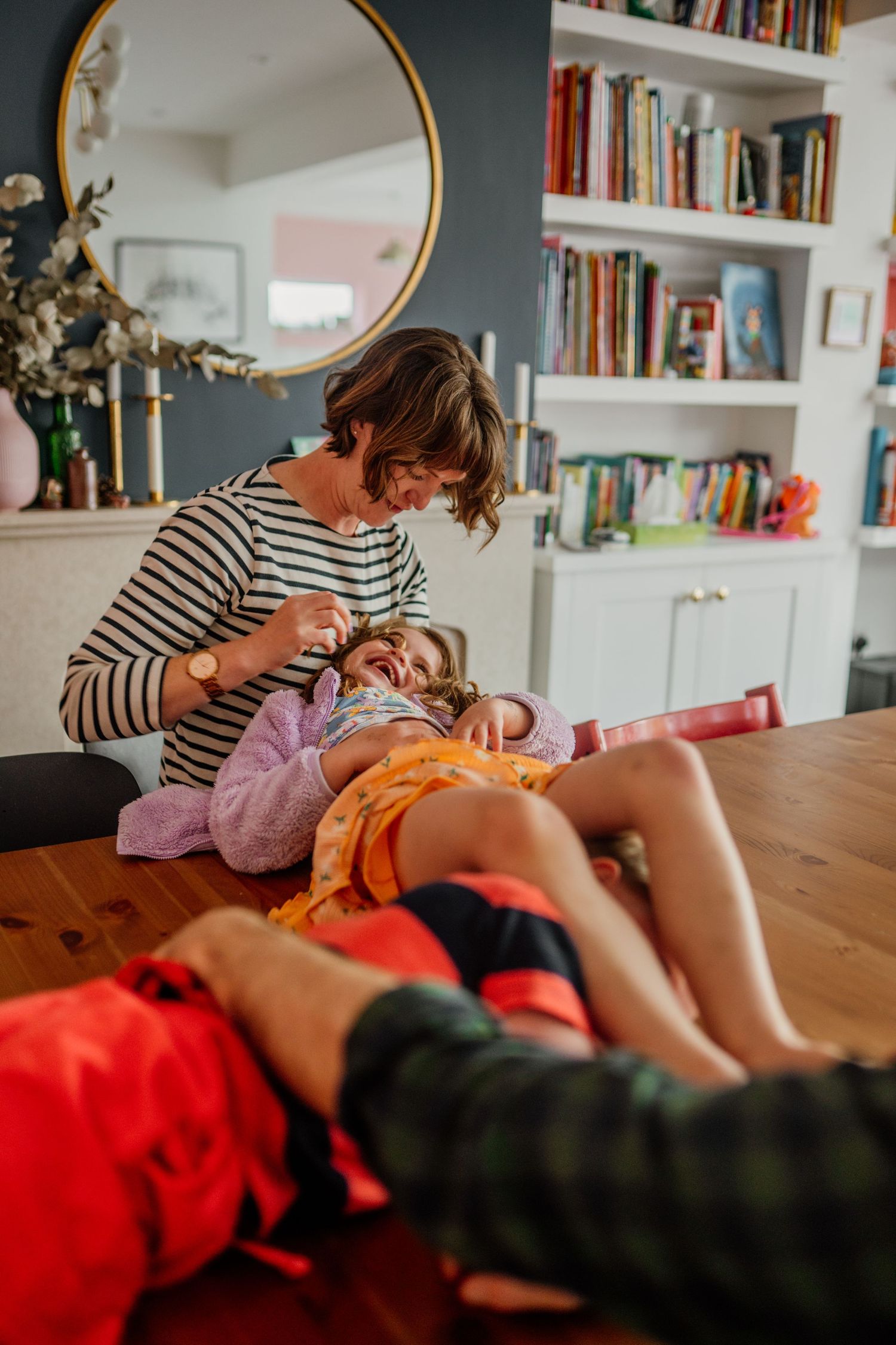 Playful tickles and giggles shared on a wooden table with red blanket.