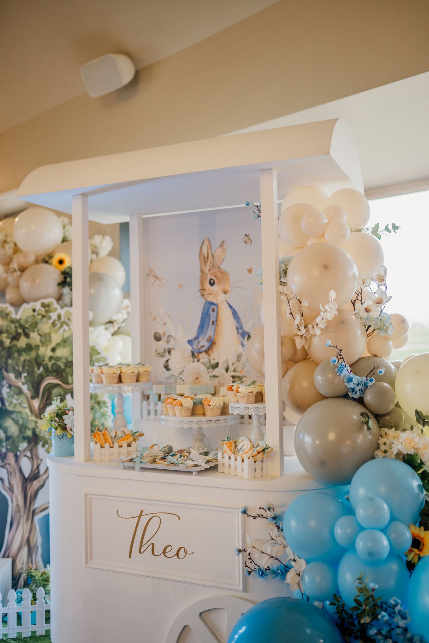 A beautifully decorated dessert table with white and blue balloon arrangements and party decor.