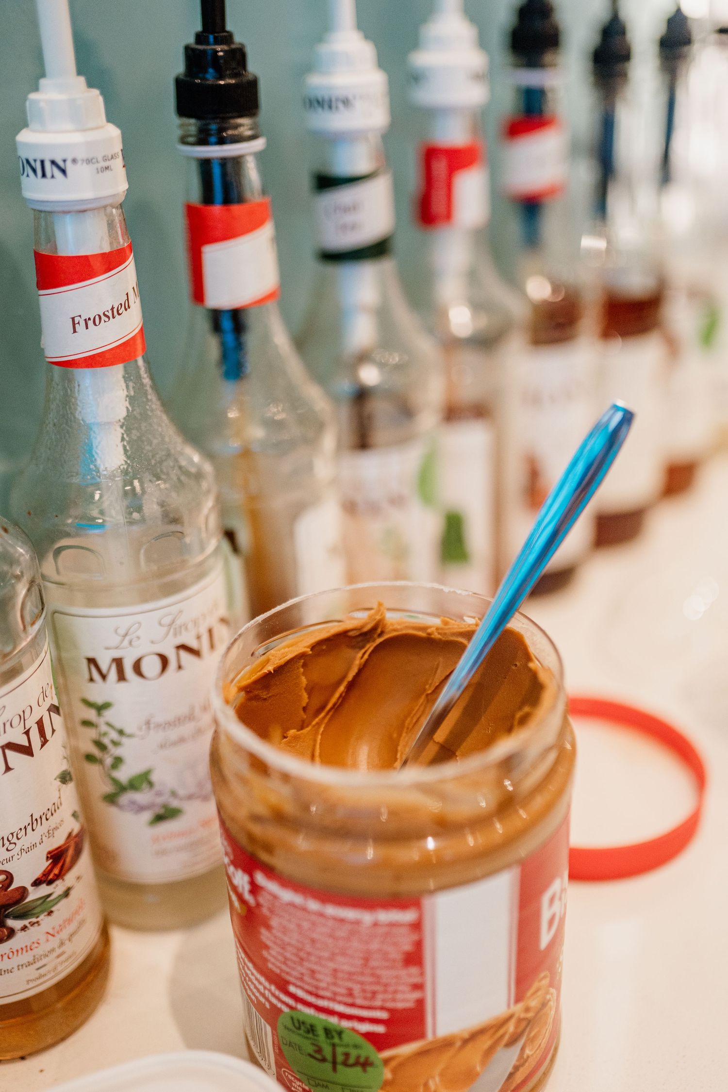 Collection of syrup bottles and coffee flavorings arranged on a counter with blue straws.