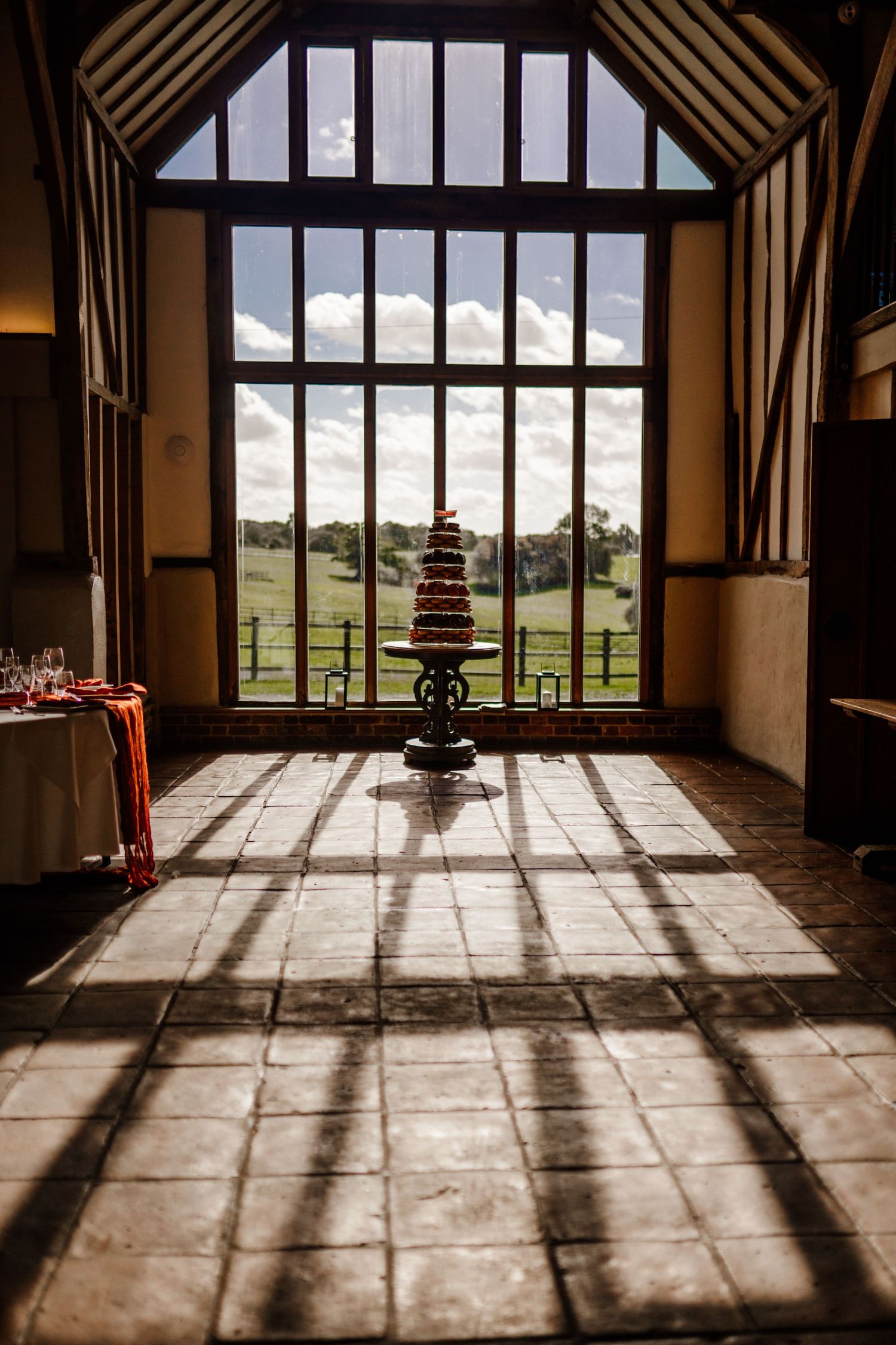 Sunlight casts dramatic shadows through windows onto stone floor in rustic barn interior creating geometric patterns.