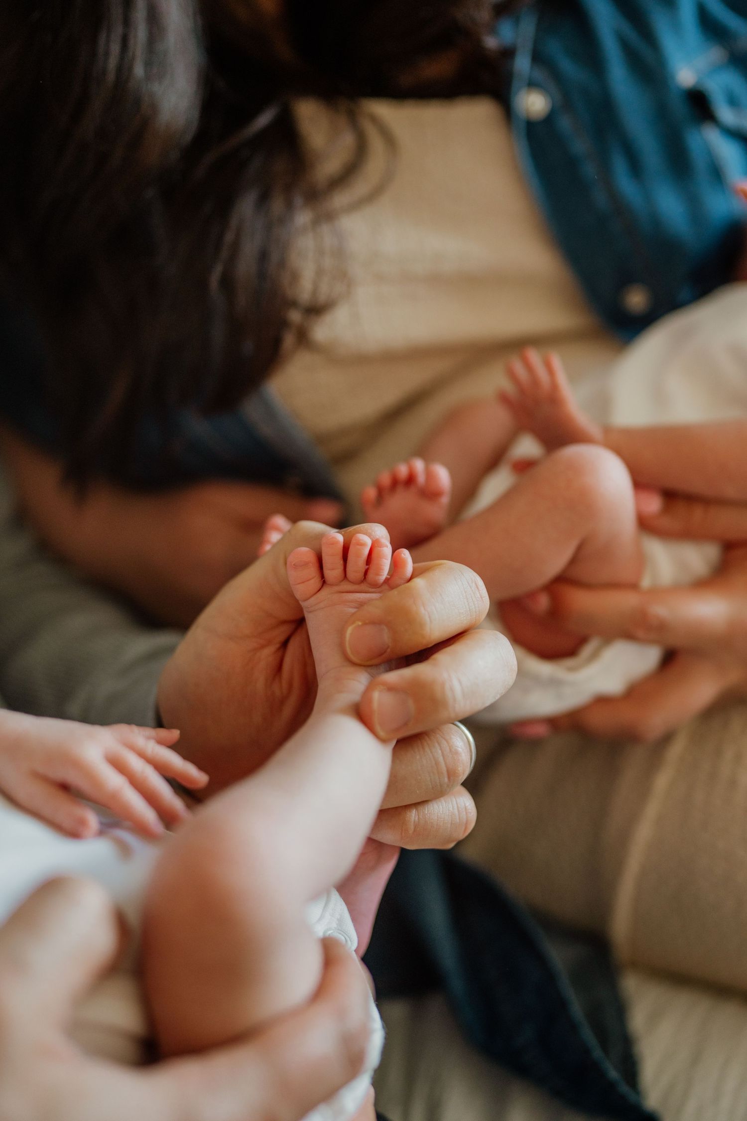 Close-up of tiny baby feet being gently massaged on soft surface.