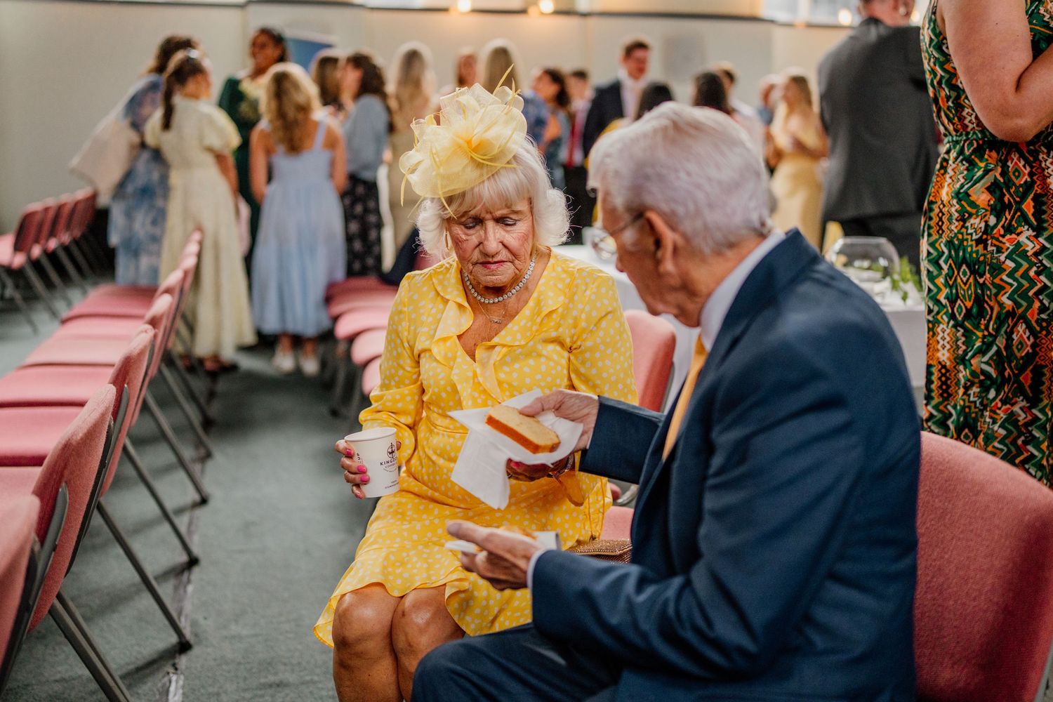 A couple in formal attire share an intimate moment at what appears to be a wedding reception or celebration.