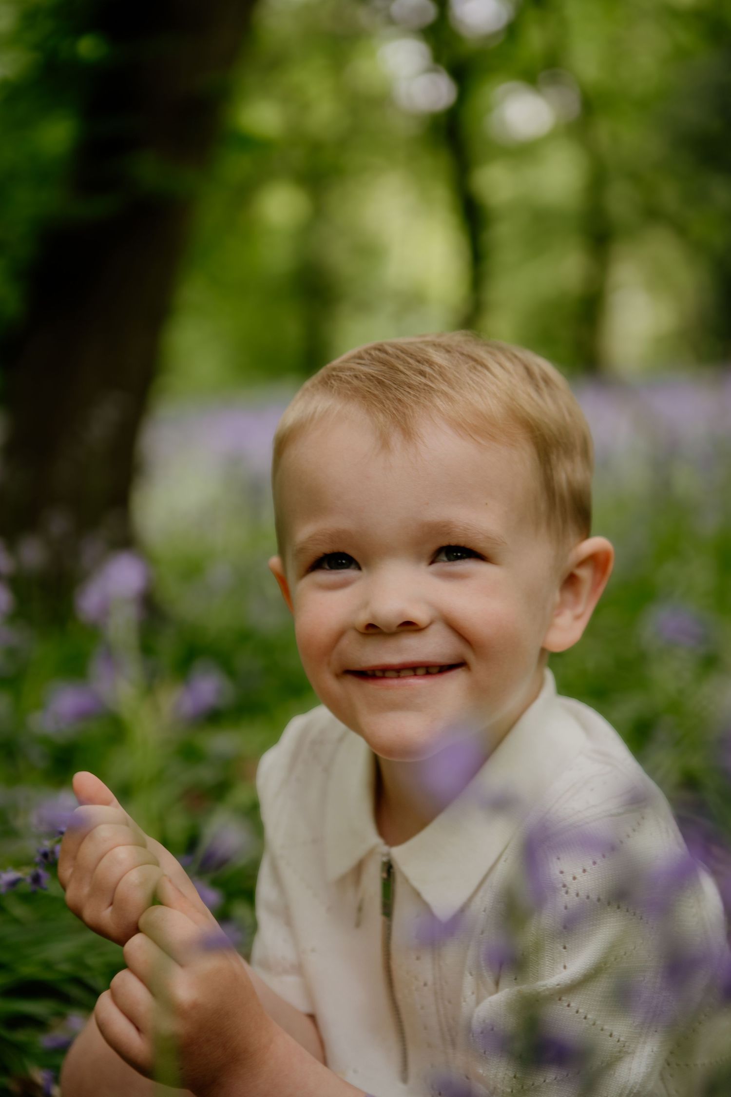 a little boy sat smiling in the bluebells in Hertfordshire