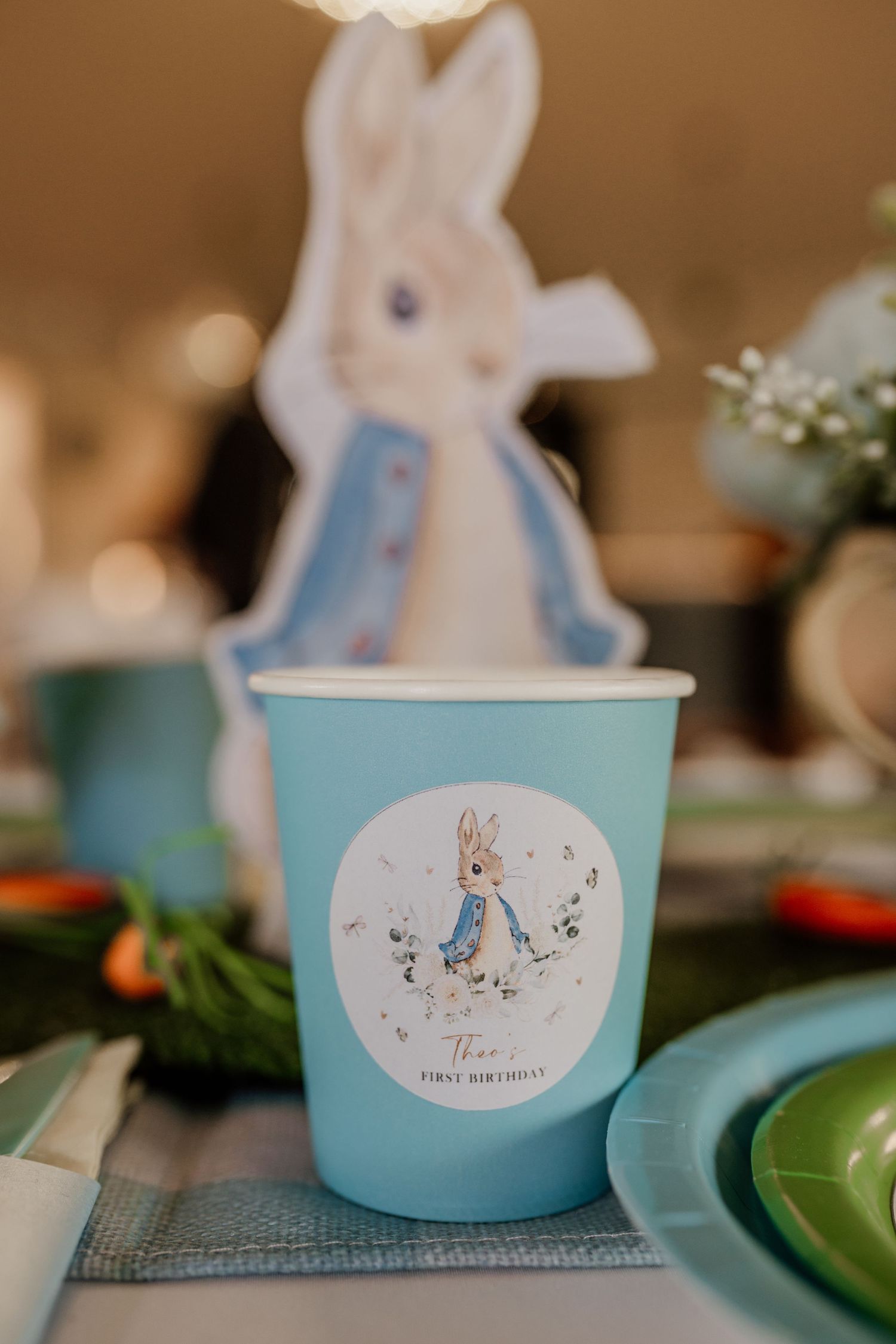 Light blue party cups with bunny illustrations set on a decorated table.