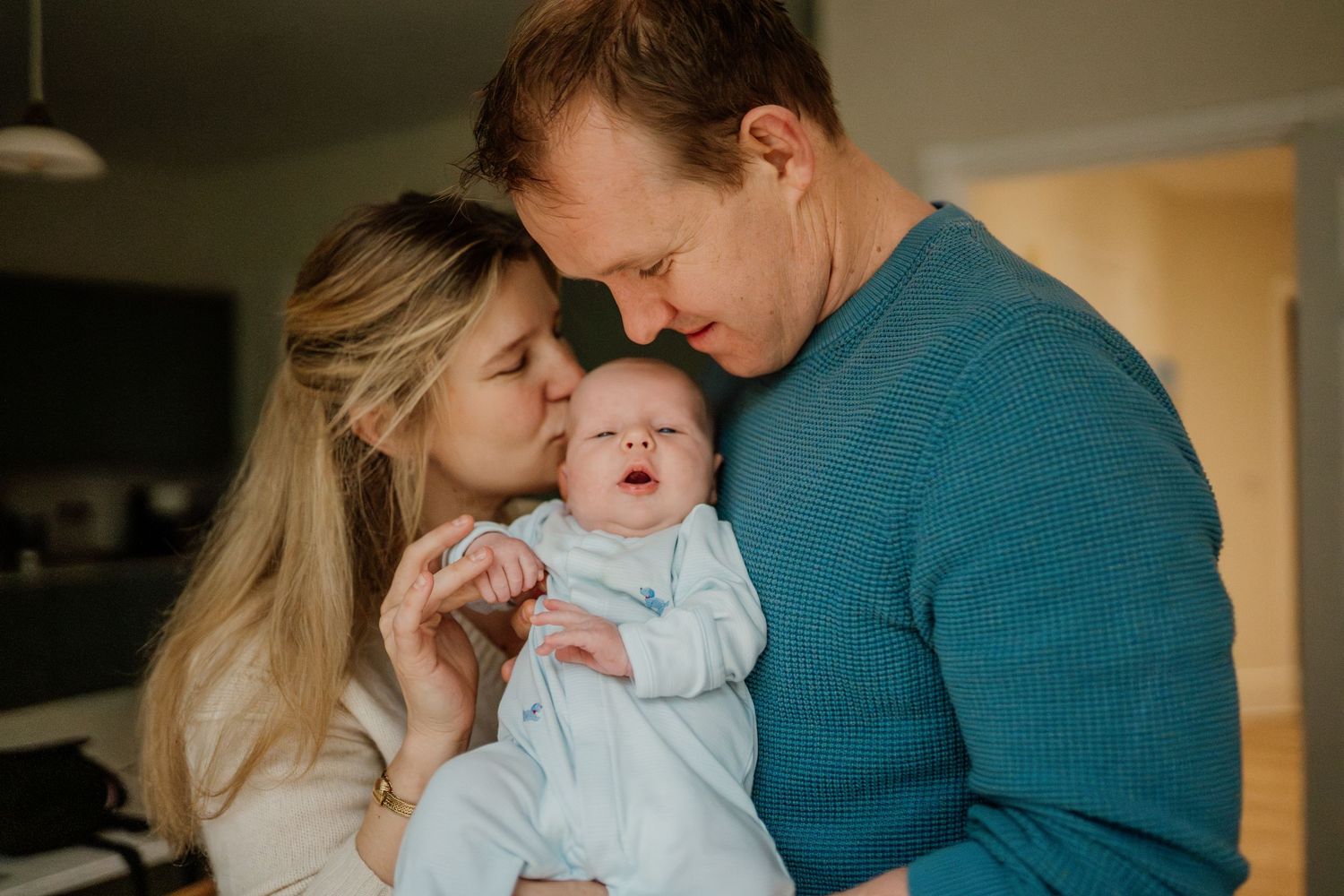 Family sharing tender moment with newborn in cozy home setting.