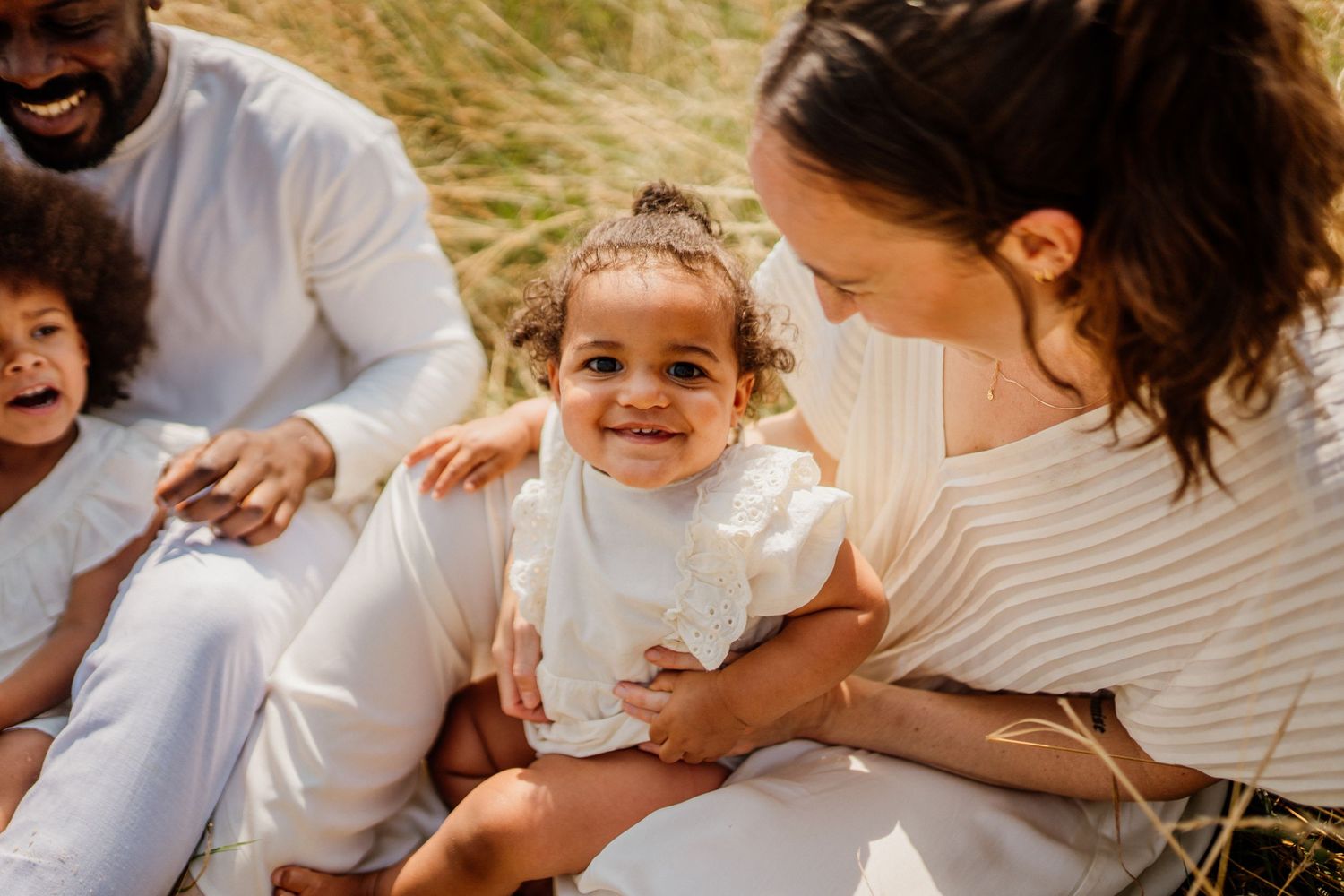Family sharing joyful moments together outdoors in white summer clothing.