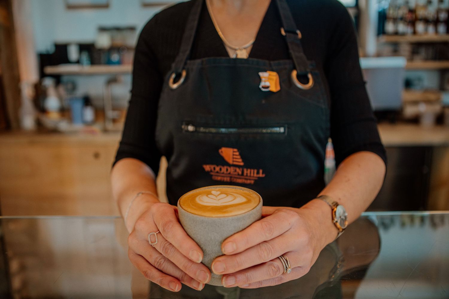 Close-up view of hands holding a warm cup of coffee at a cafe counter.
