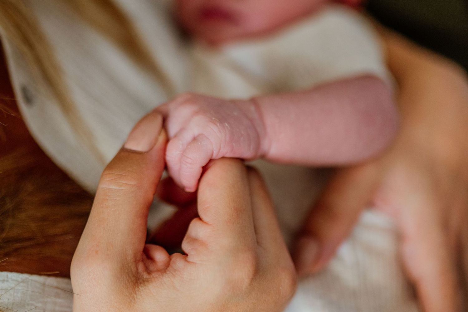 Close up of tiny newborn baby feet and hands being gently held.