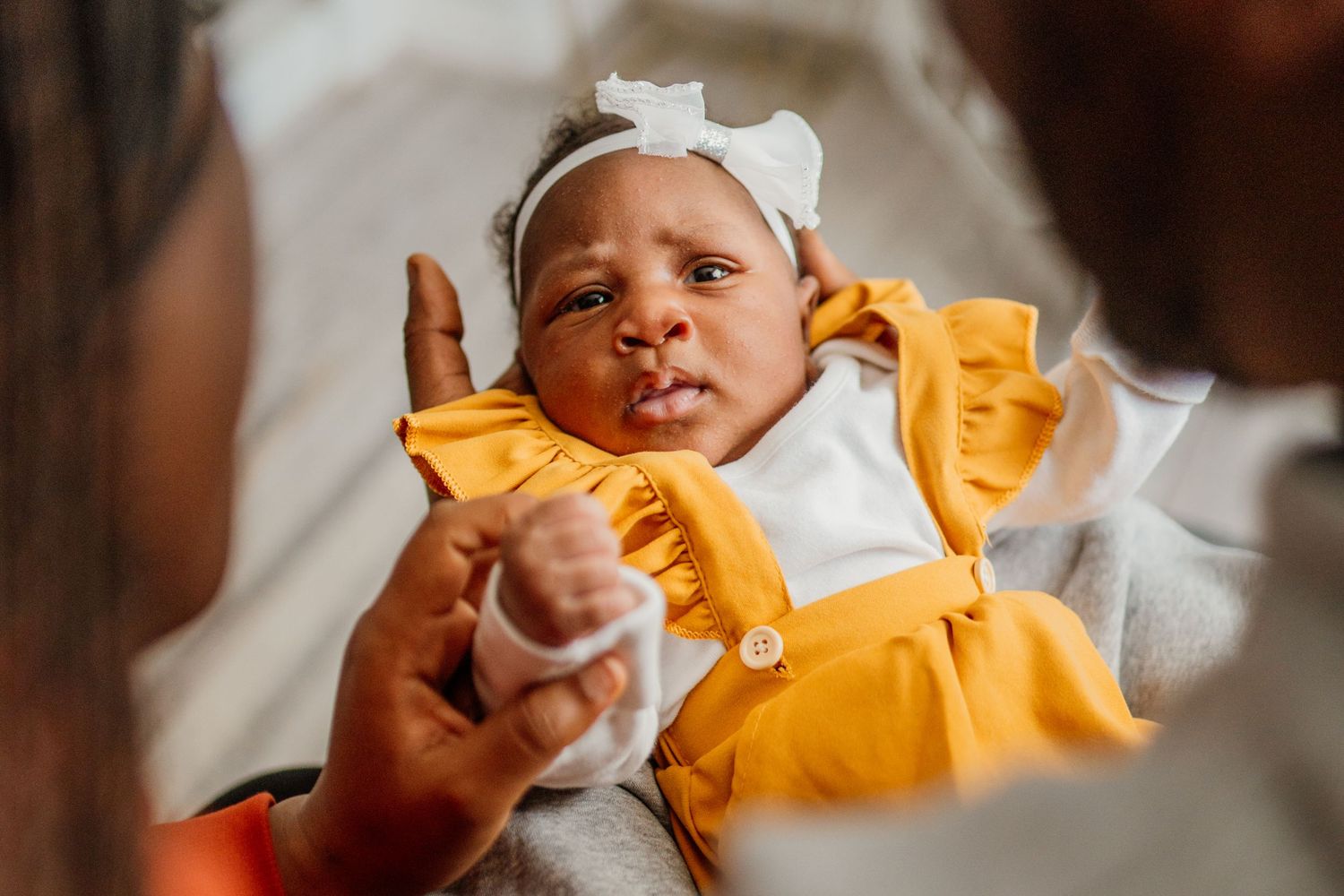 Baby wearing yellow and white outfit in a series of candid expressions.