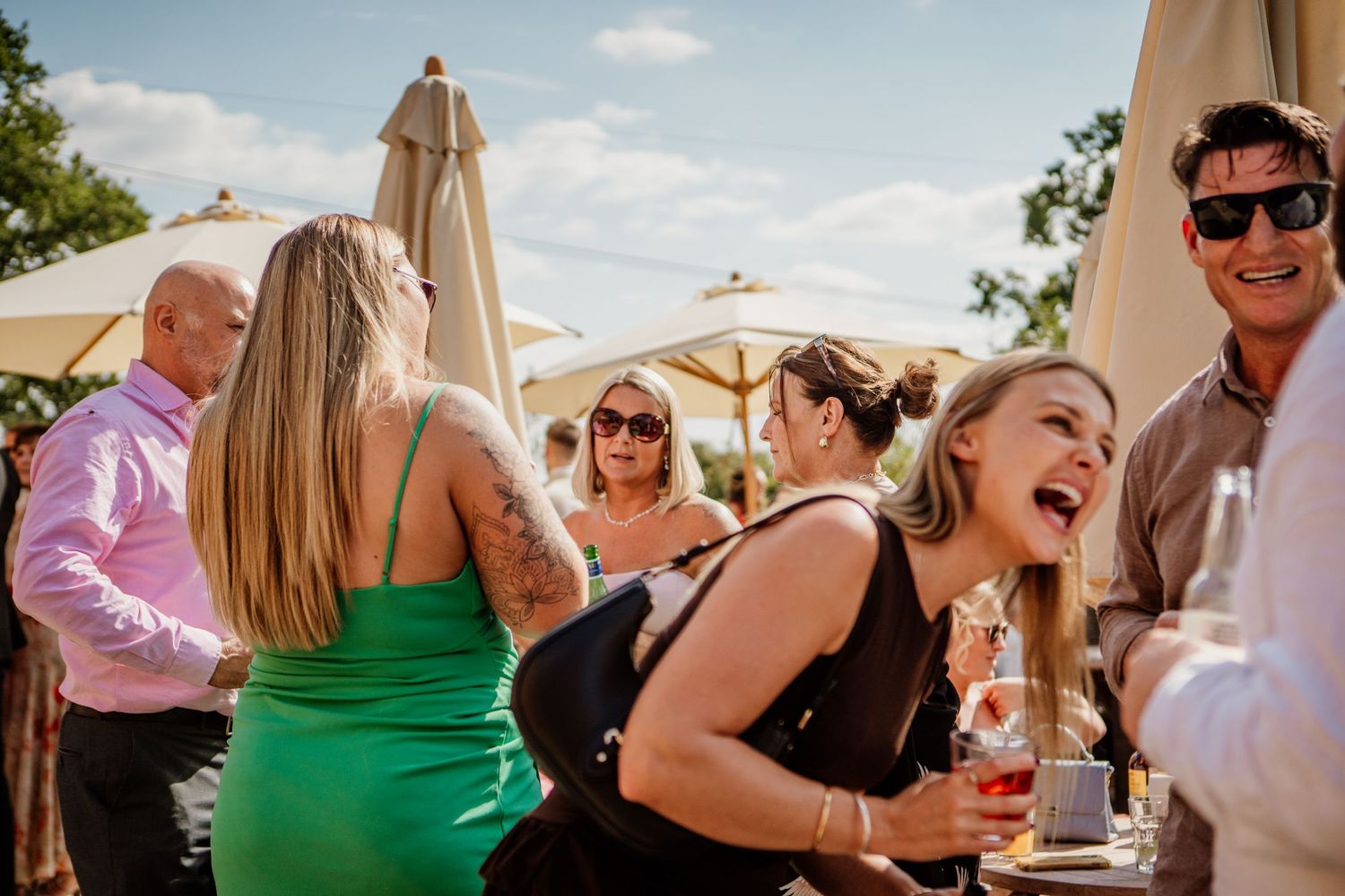 Wedding guests enjoying drinks and conversation on sunny outdoor patio.