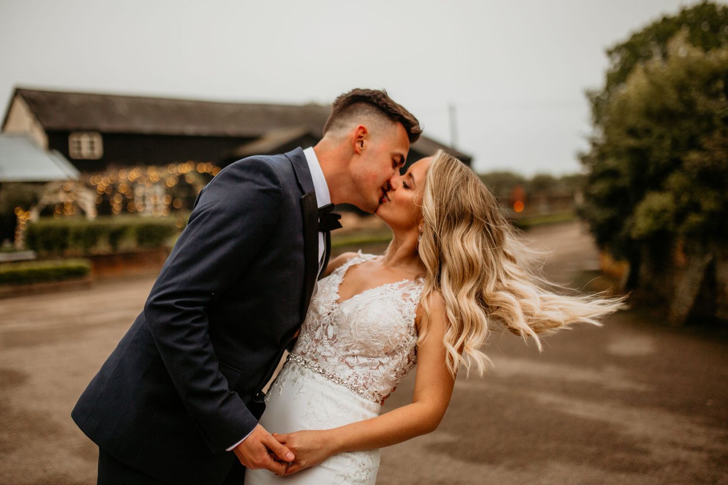 Romantic outdoor portrait of a couple in wedding attire with wind-swept hair.