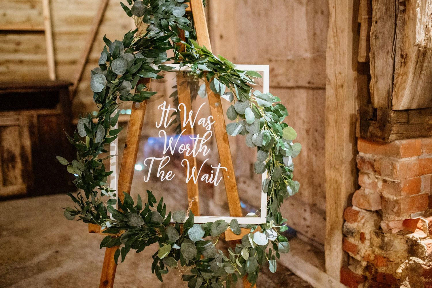 Rustic wedding venue interior with exposed brick walls and greenery decorations.