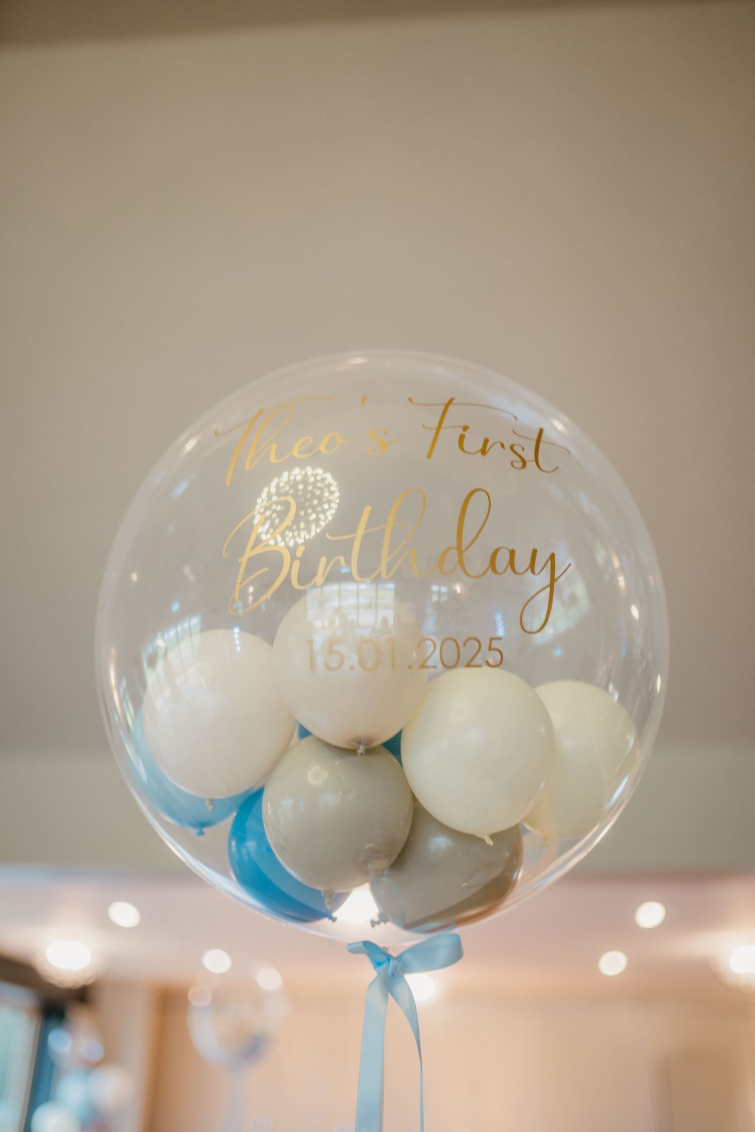 Clear balloons with gold lettering and blue accents arranged as party decorations.