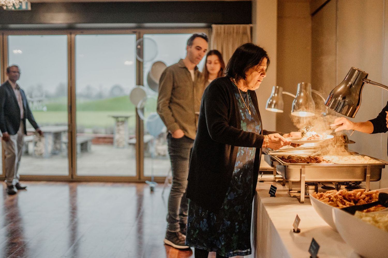 People gathering around a buffet table at an indoor event.