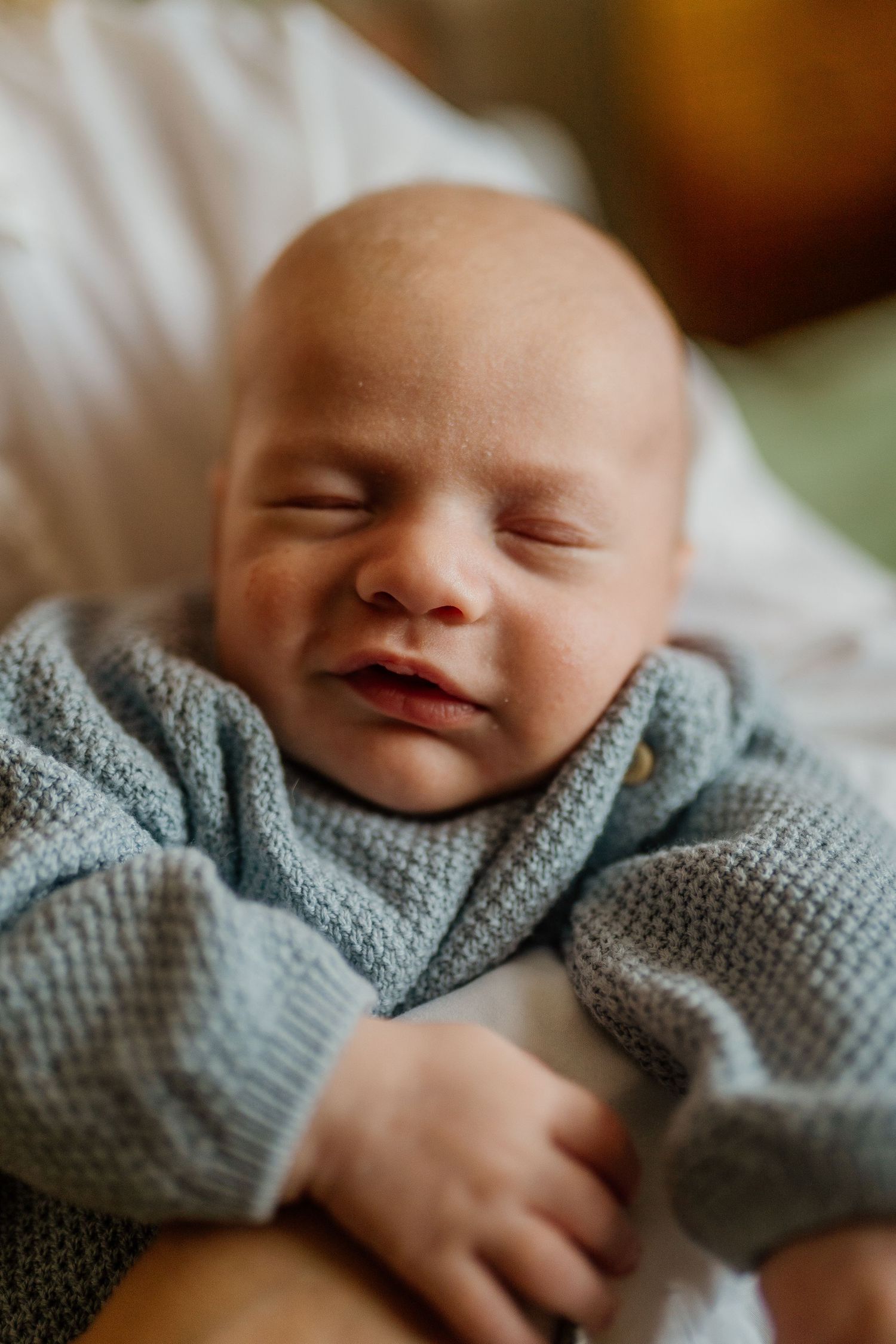 Sleeping newborn baby wearing soft blue knit sweater.