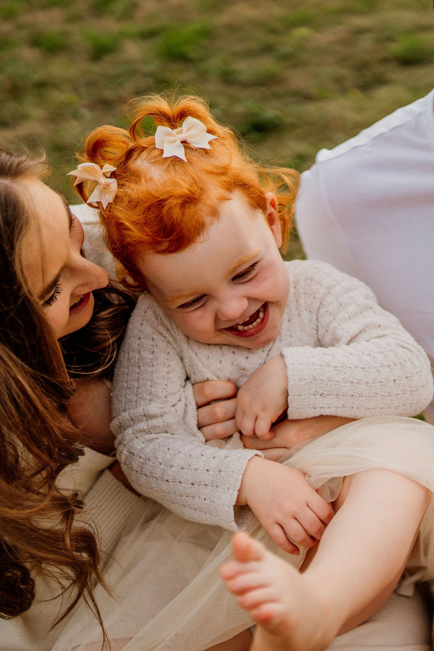 A joyful moment of laughter and cuddles captured in soft white clothing.