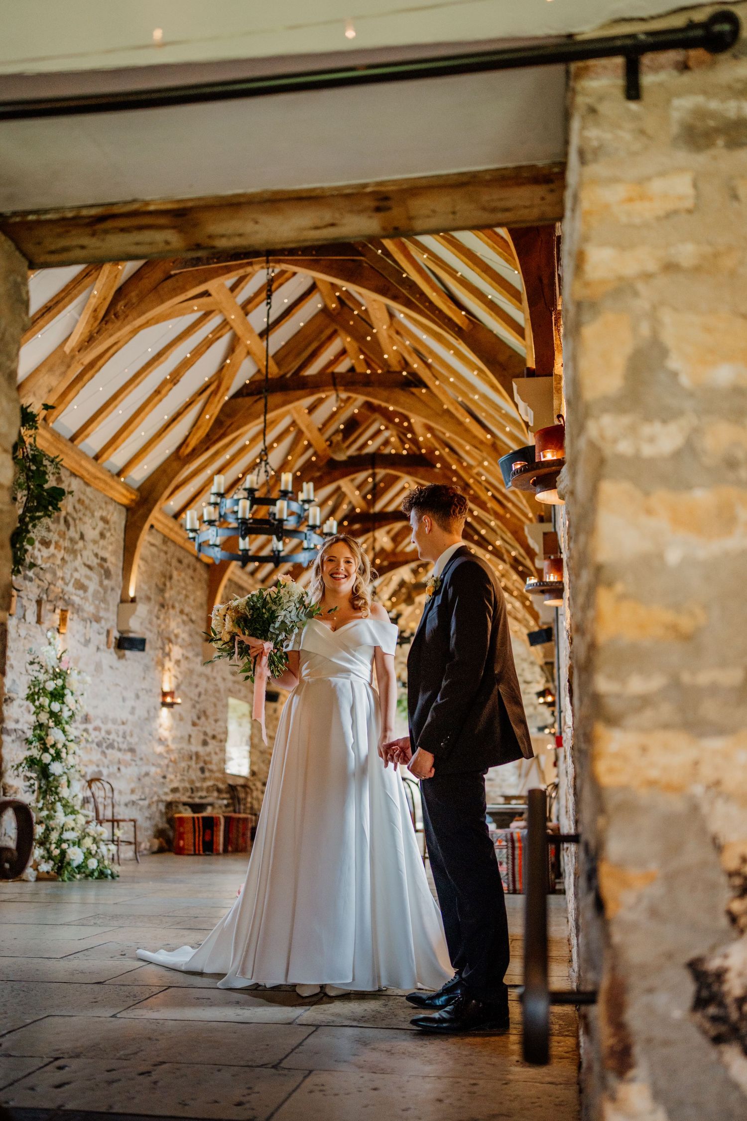 A couple shares an intimate moment under rustic wooden beams in a historic stone venue.