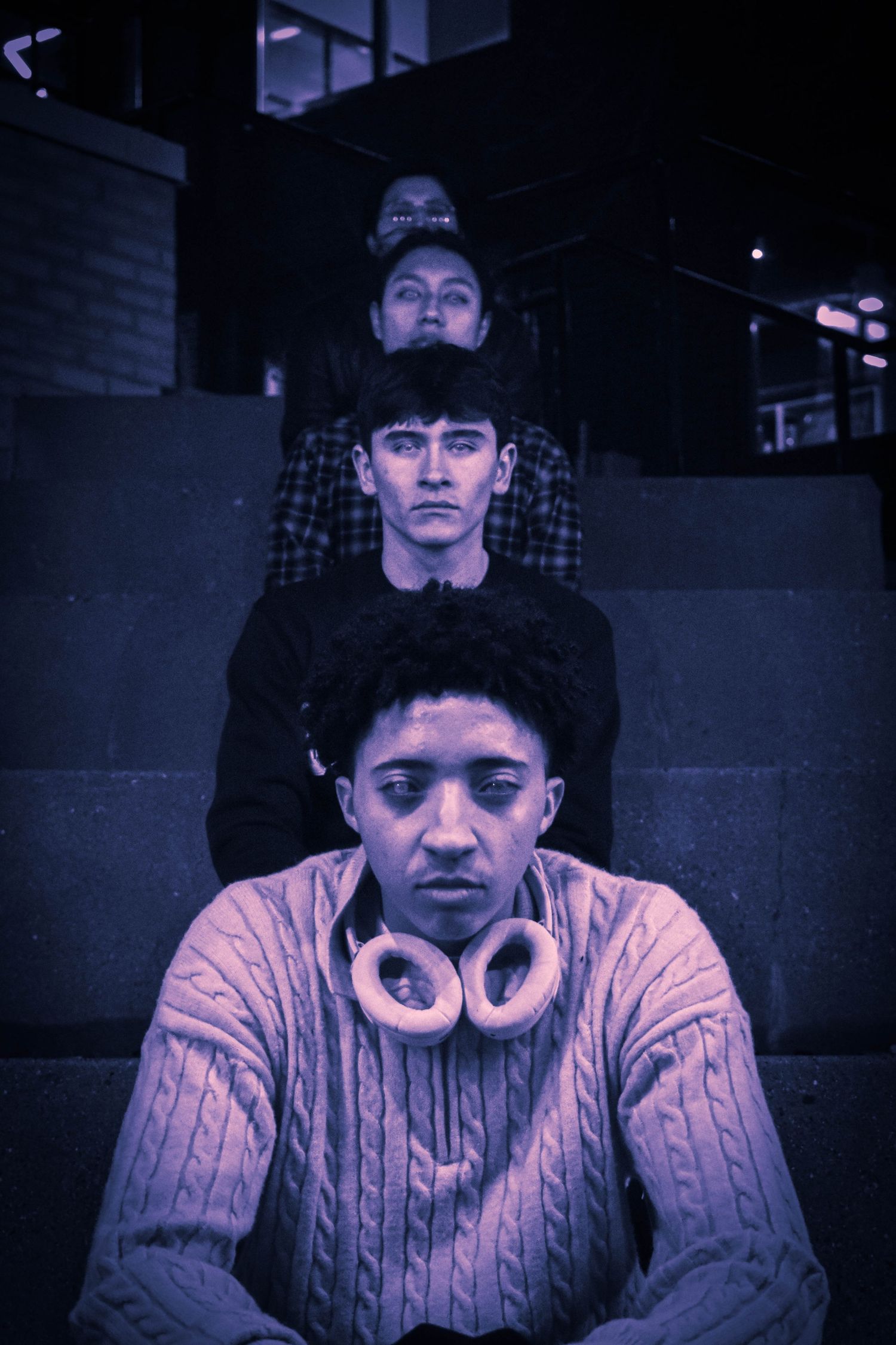 Group sitting indoors in purple lighting wearing casual clothes and headphones.