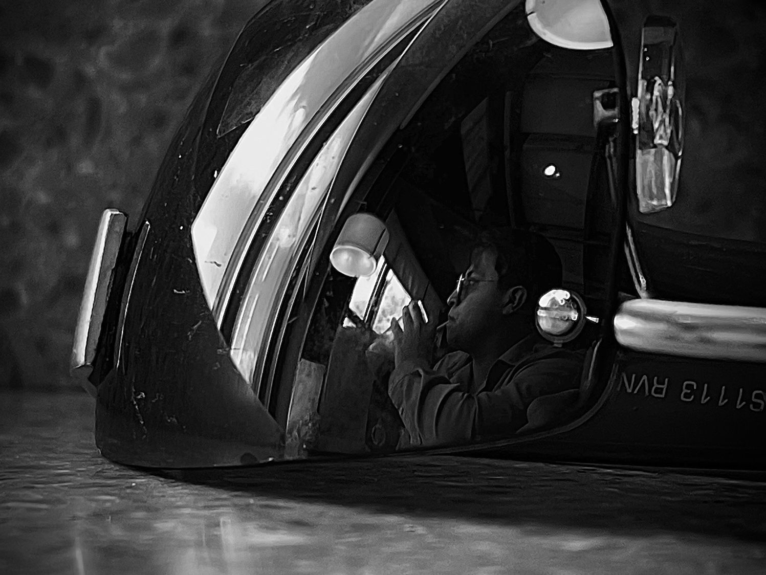 Black and white image showing silhouettes through car windows at night.