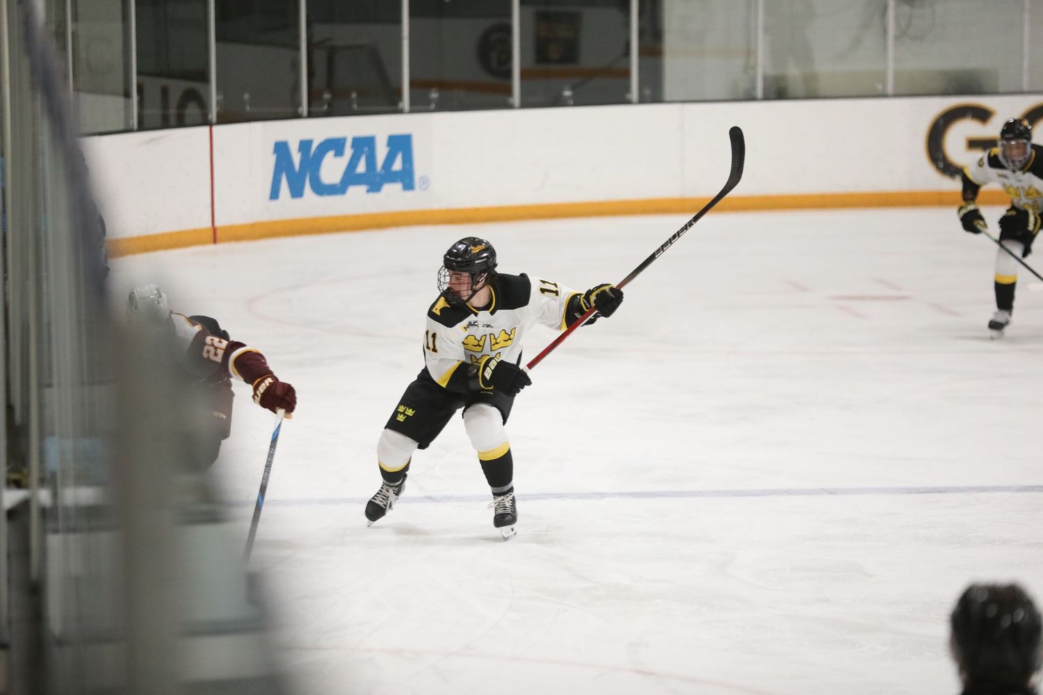 Ice hockey players skating on a rink during an NCAA game.
