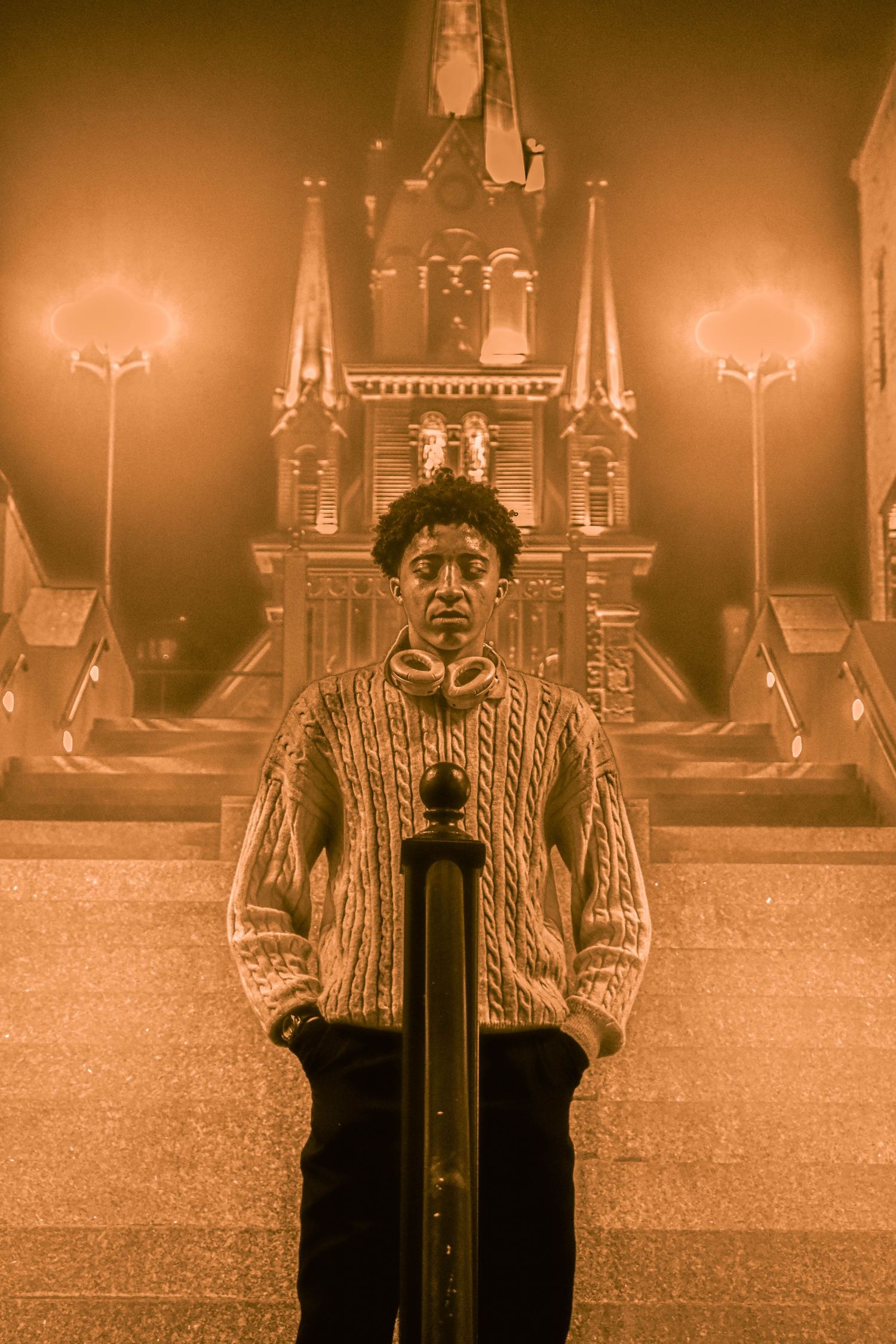 Sepia-toned image of a figure standing in front of illuminated architecture at night.