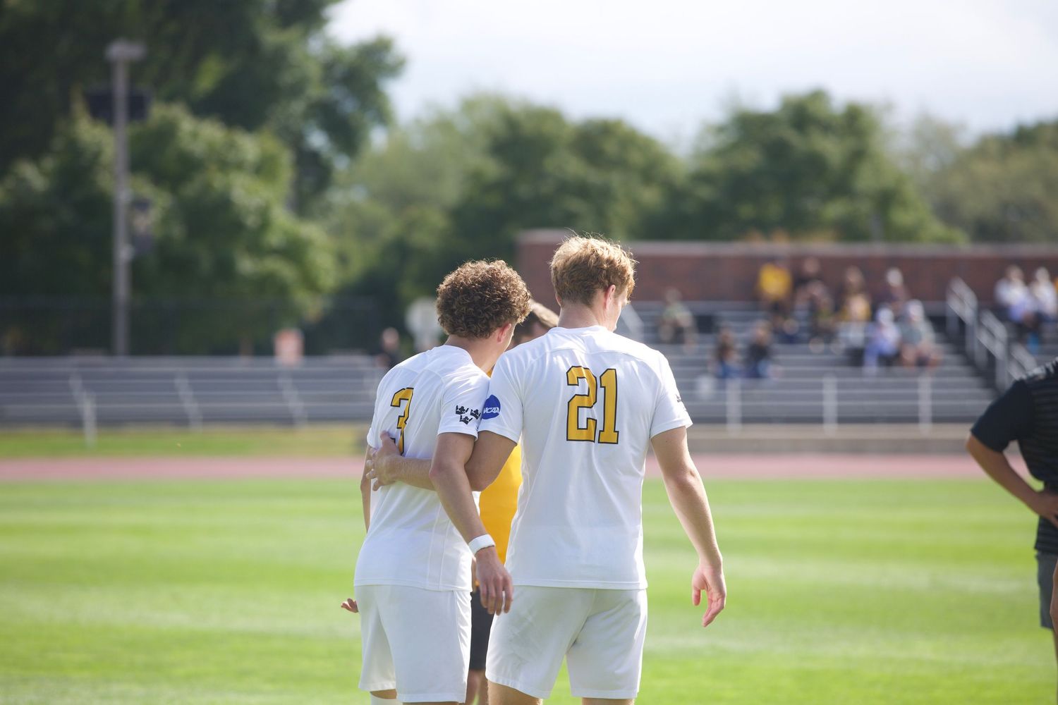 Athletes in yellow and white uniforms spread out across a soccer field during a match.