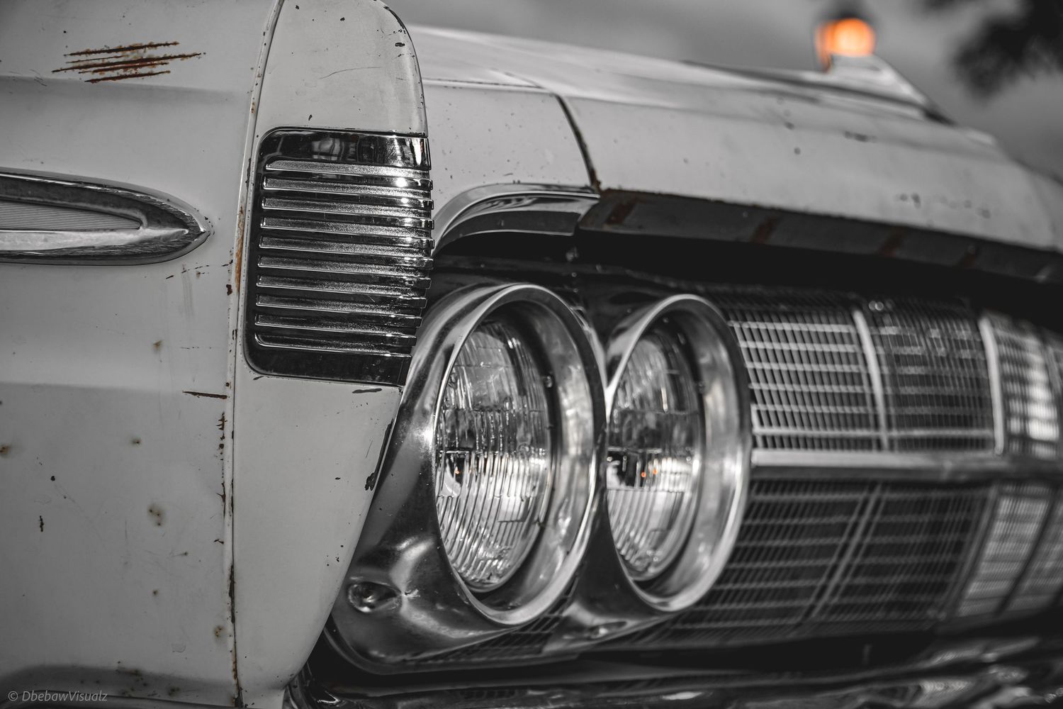 Close-up of a rusty vintage car front with dual round headlights in black and white photography.