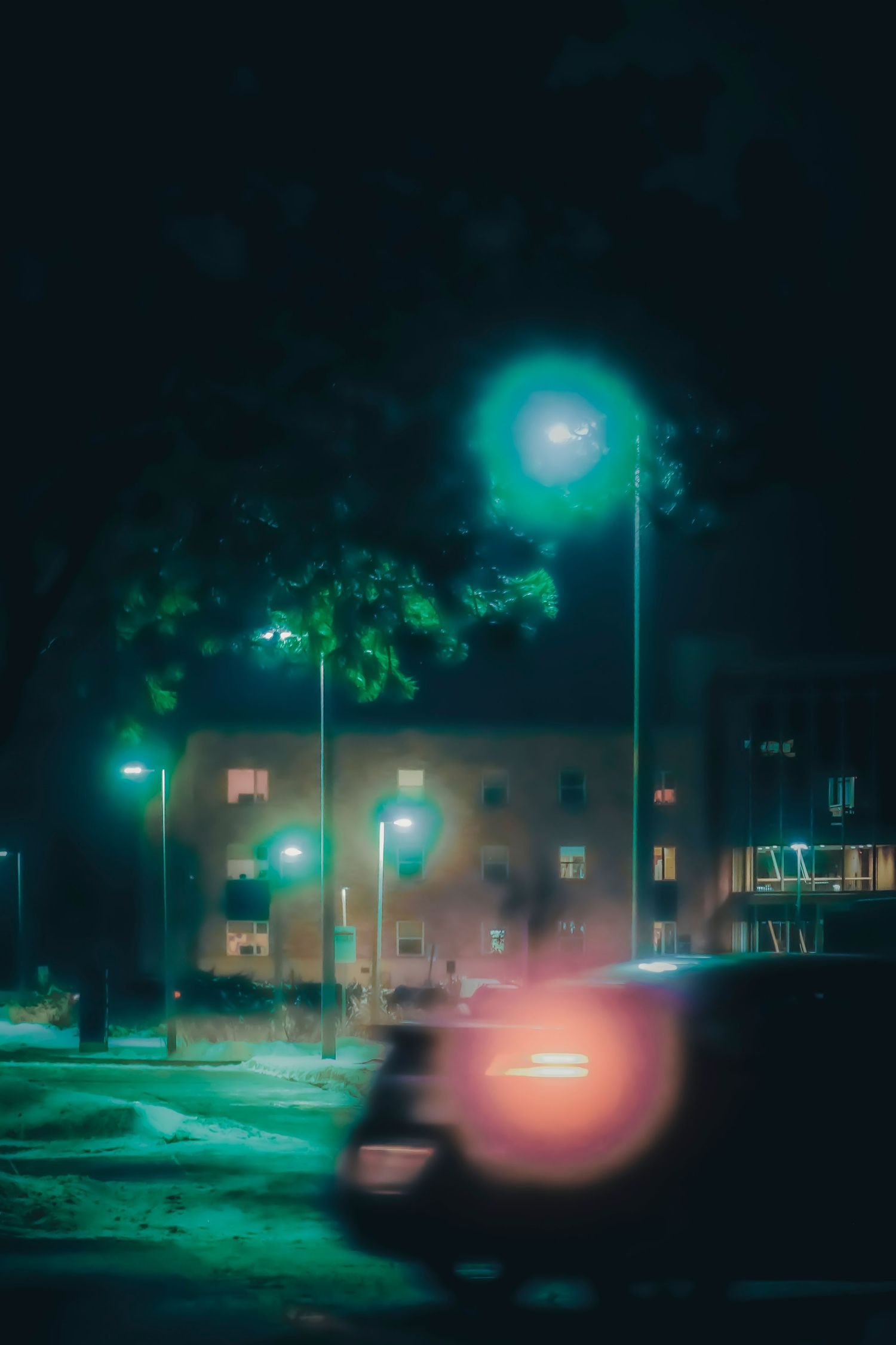 Nighttime street scene with teal streetlights and blurred car lights.