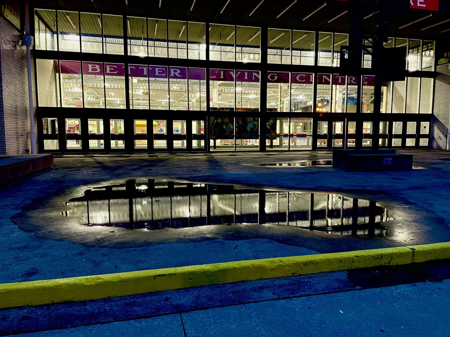 Exterior view of an empty sidewalk puddle pool with a reflective water surface.
