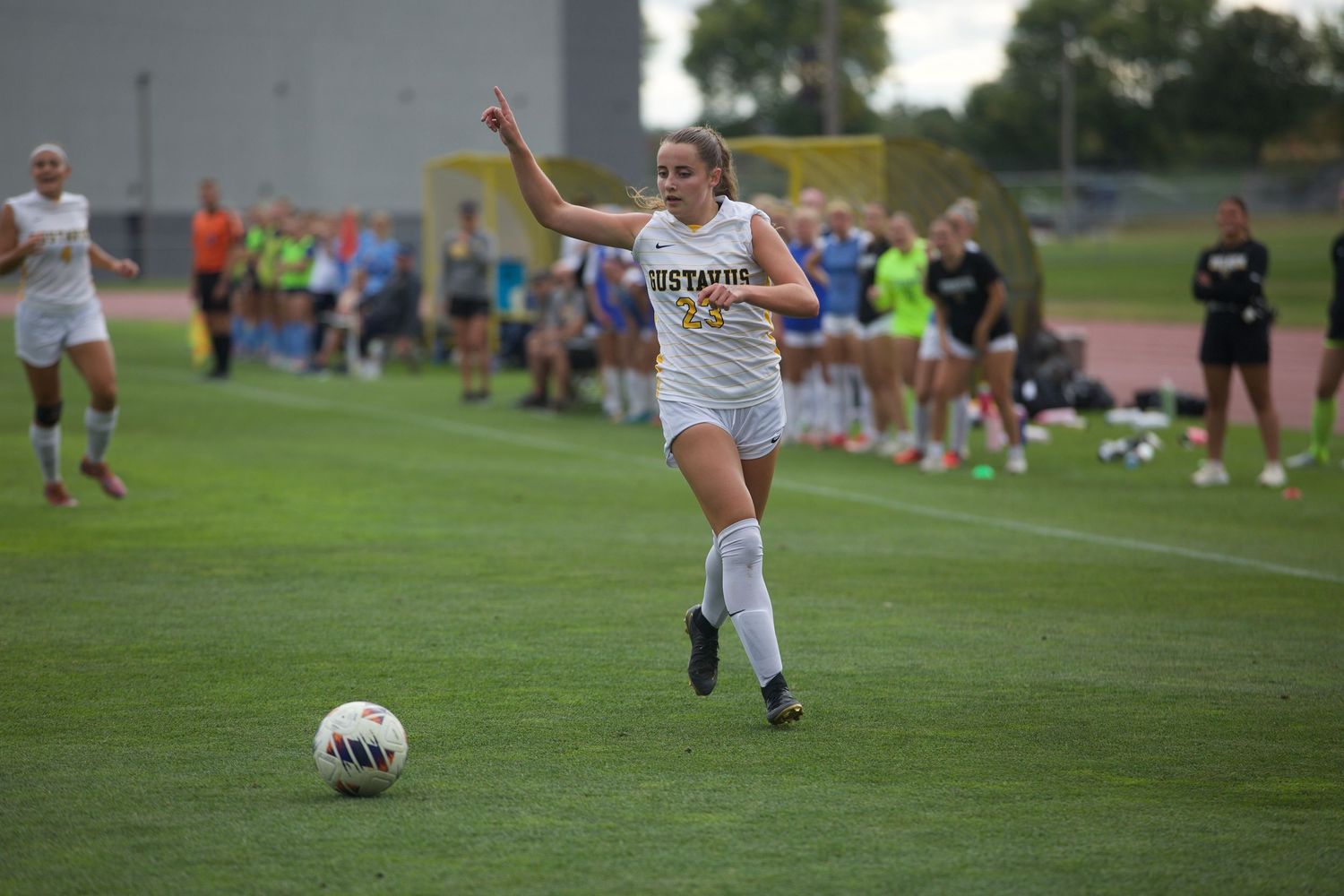 Soccer players run across a grass field during a match.