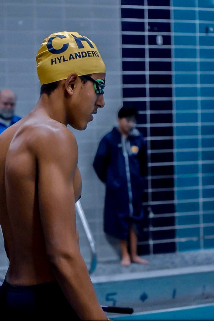 Swimmer in yellow cap and goggles prepares at poolside before competition.