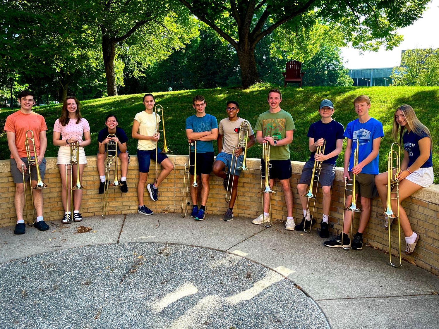 Group of people lined up against stone wall outdoors in casual summer attire.