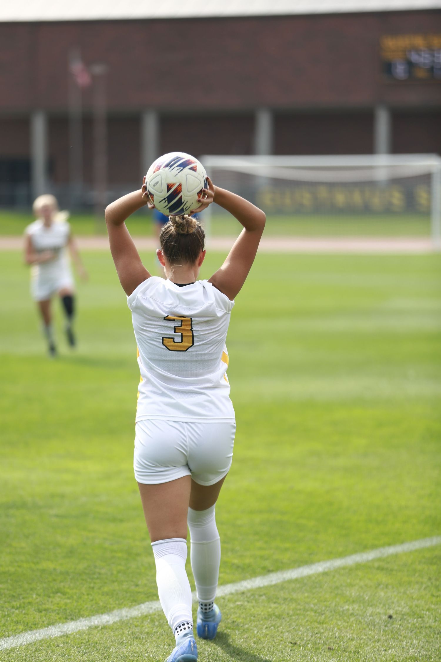 A soccer player throws a ball on the grass field during a game.