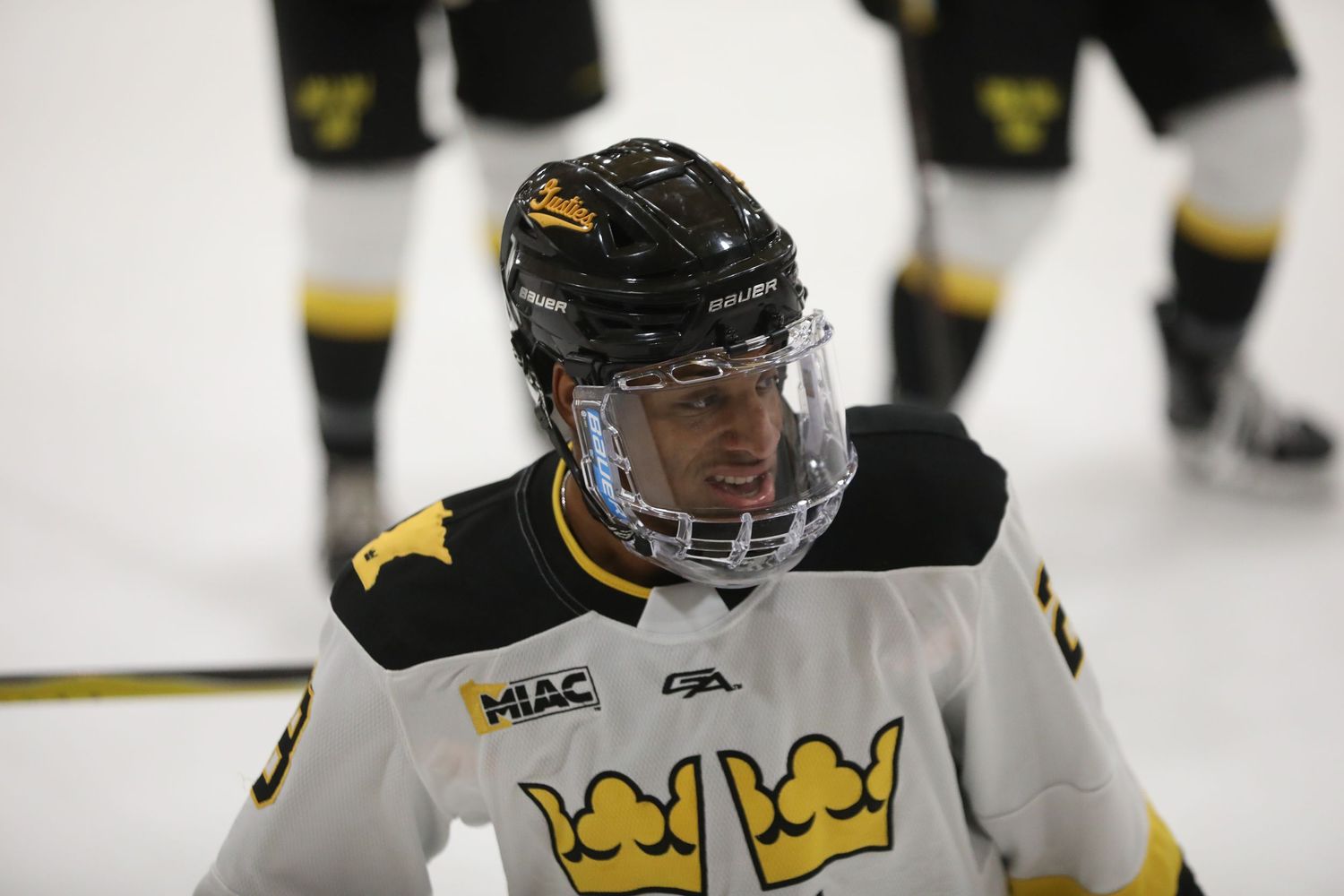 Hockey players in black and yellow uniforms compete for the puck on an ice rink during a game.