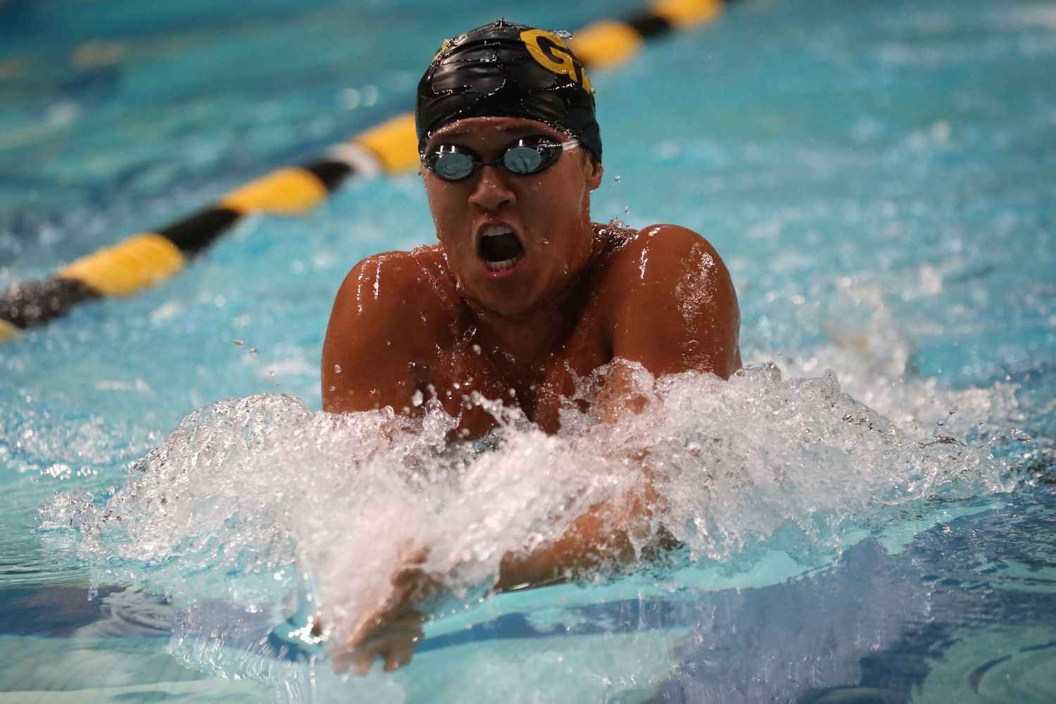 An Intense competitive swimmer performs breaststroke in a pool with lane markers visible.