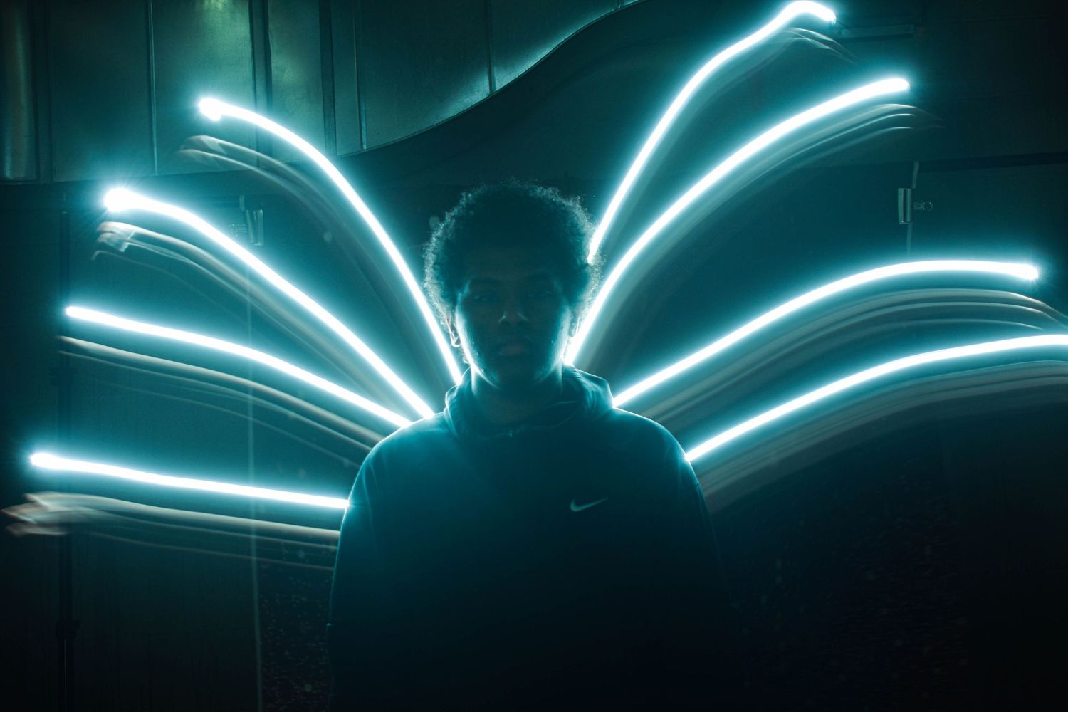 Silhouette against blue neon light trails creating wing-like patterns.