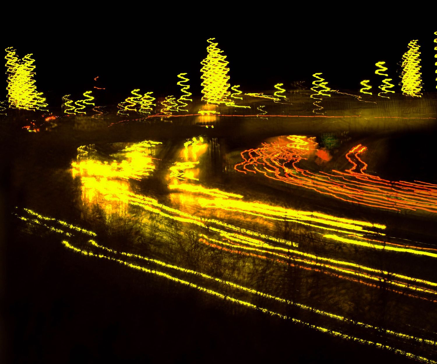 Long exposure night photography showing streaks of yellow light trails along a dark road.