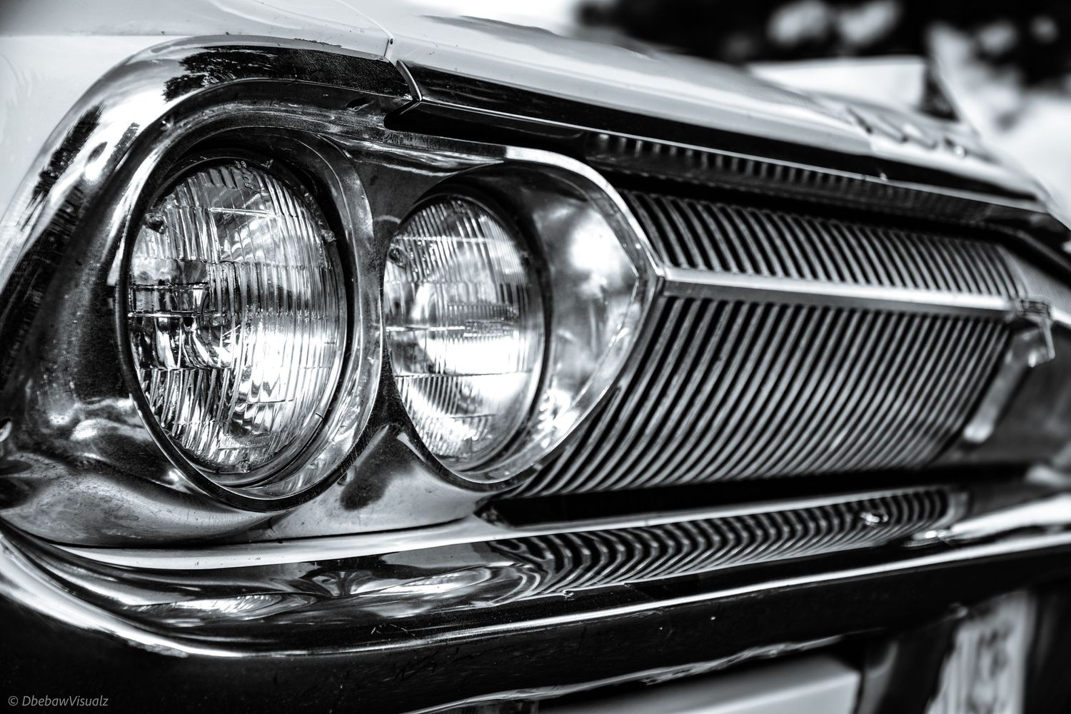 Black and white close-up of a classic vintage car dual headlights and chrome grille, showcasing retro automotive design.