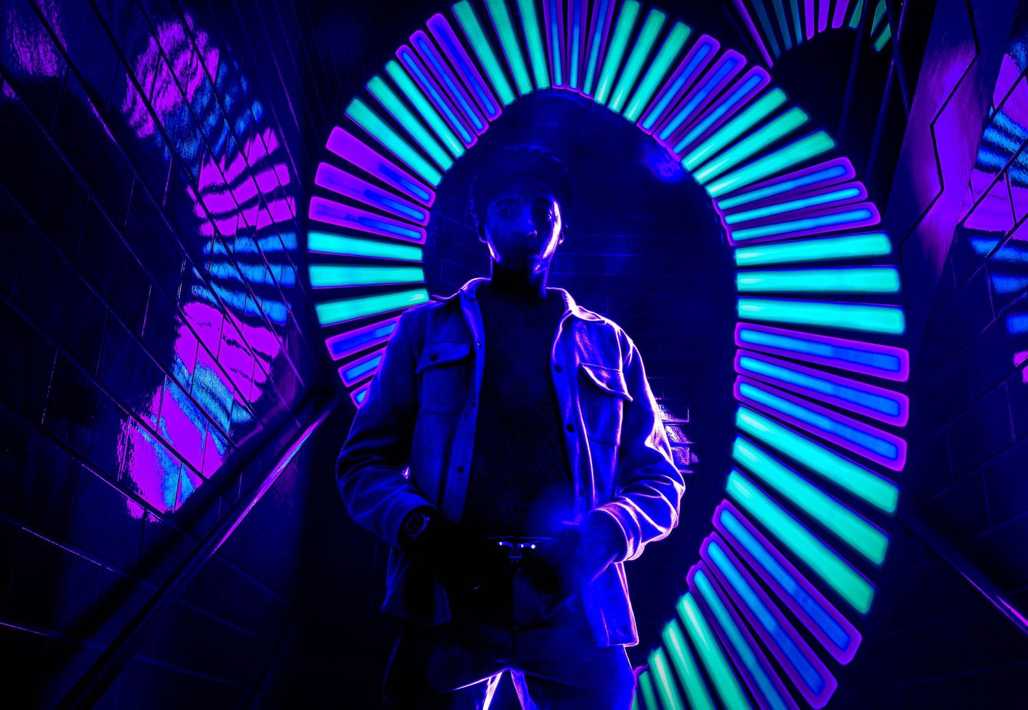 Silhouette posing against neon blue and purple circular light patterns.
