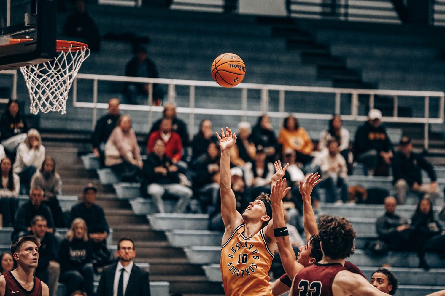 Basketball players competing for a rebound during an intense game in a gymnasium.