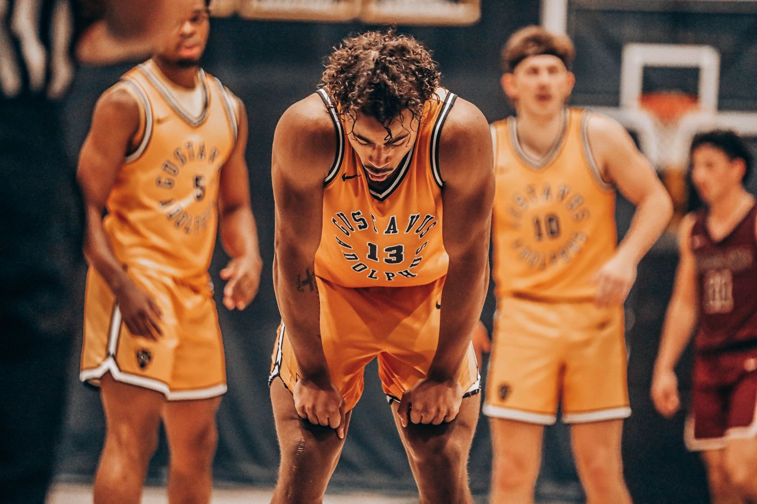 Basketball players in orange jerseys positioning themselves during a competitive game.
