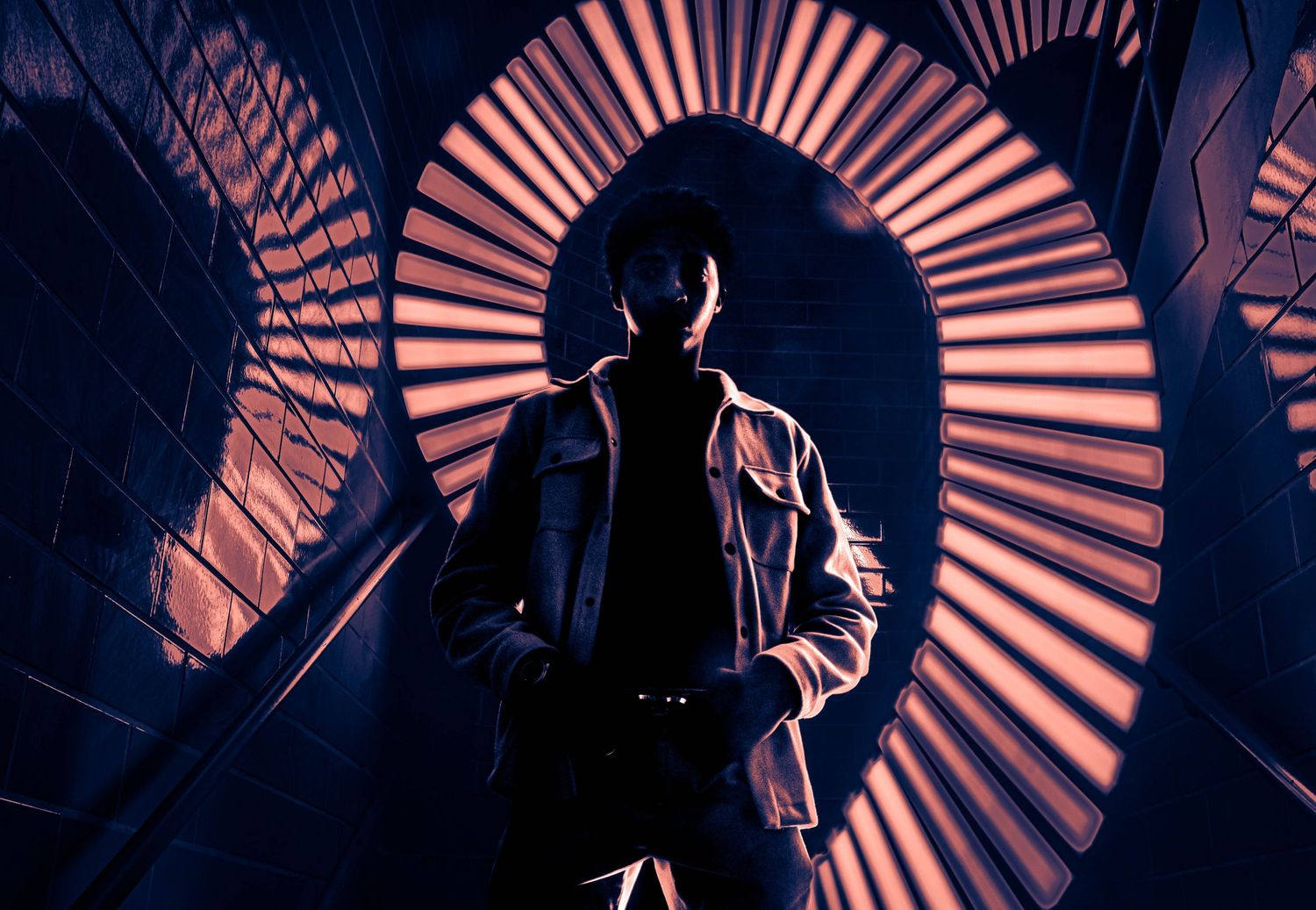 Silhouettes against circular radial pattern background in dark blue and orange tones.