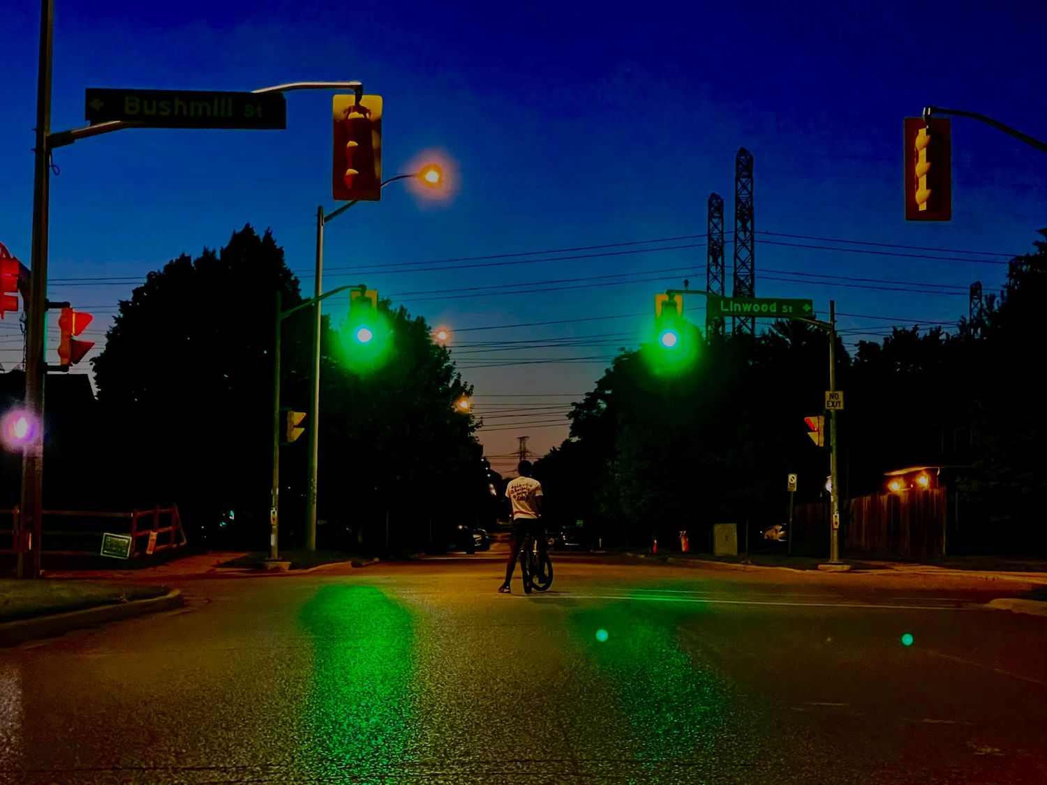 Street intersection at dusk with traffic lights and street lamps creating ambient glow.